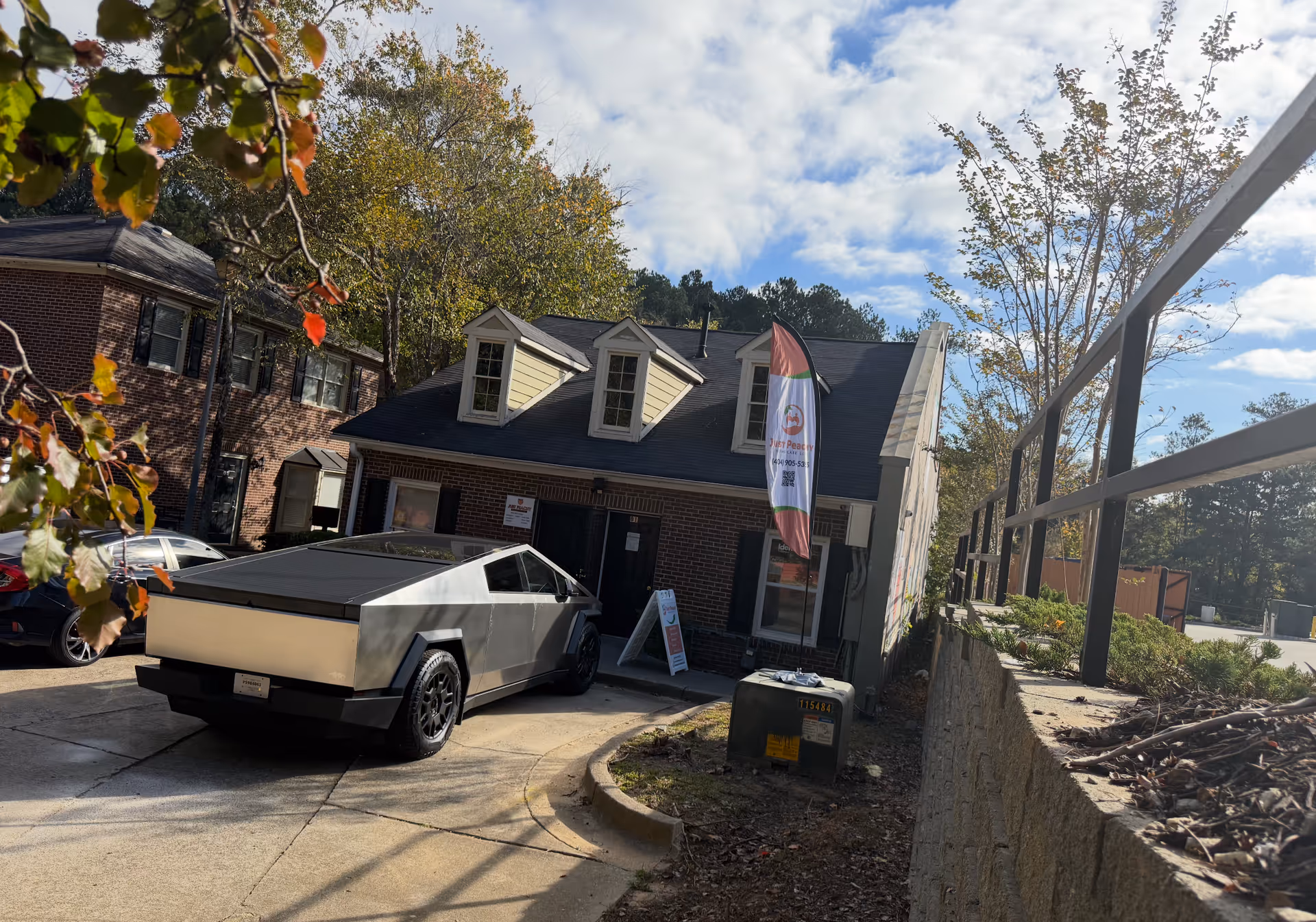 Brick senior care building with dormers, a banner flag, and a futuristic car in the driveway.