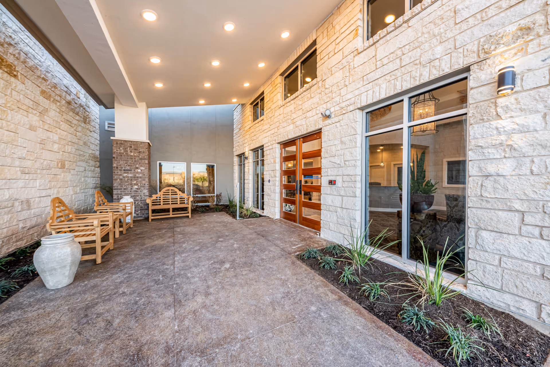 Covered outdoor entrance with stone walls, wooden benches, and glass doors.