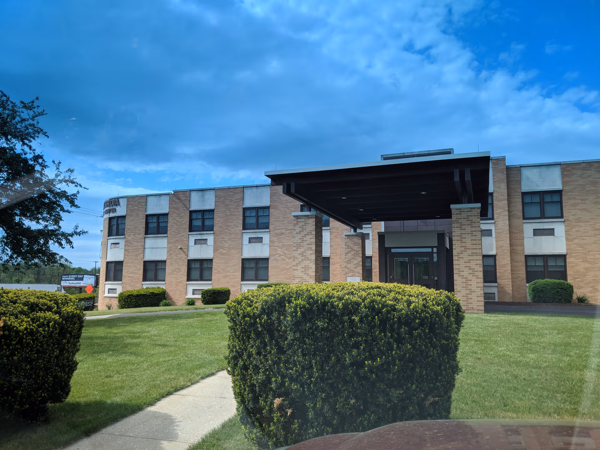 Exterior view of a brick senior living center with a covered entrance and manicured lawn.
