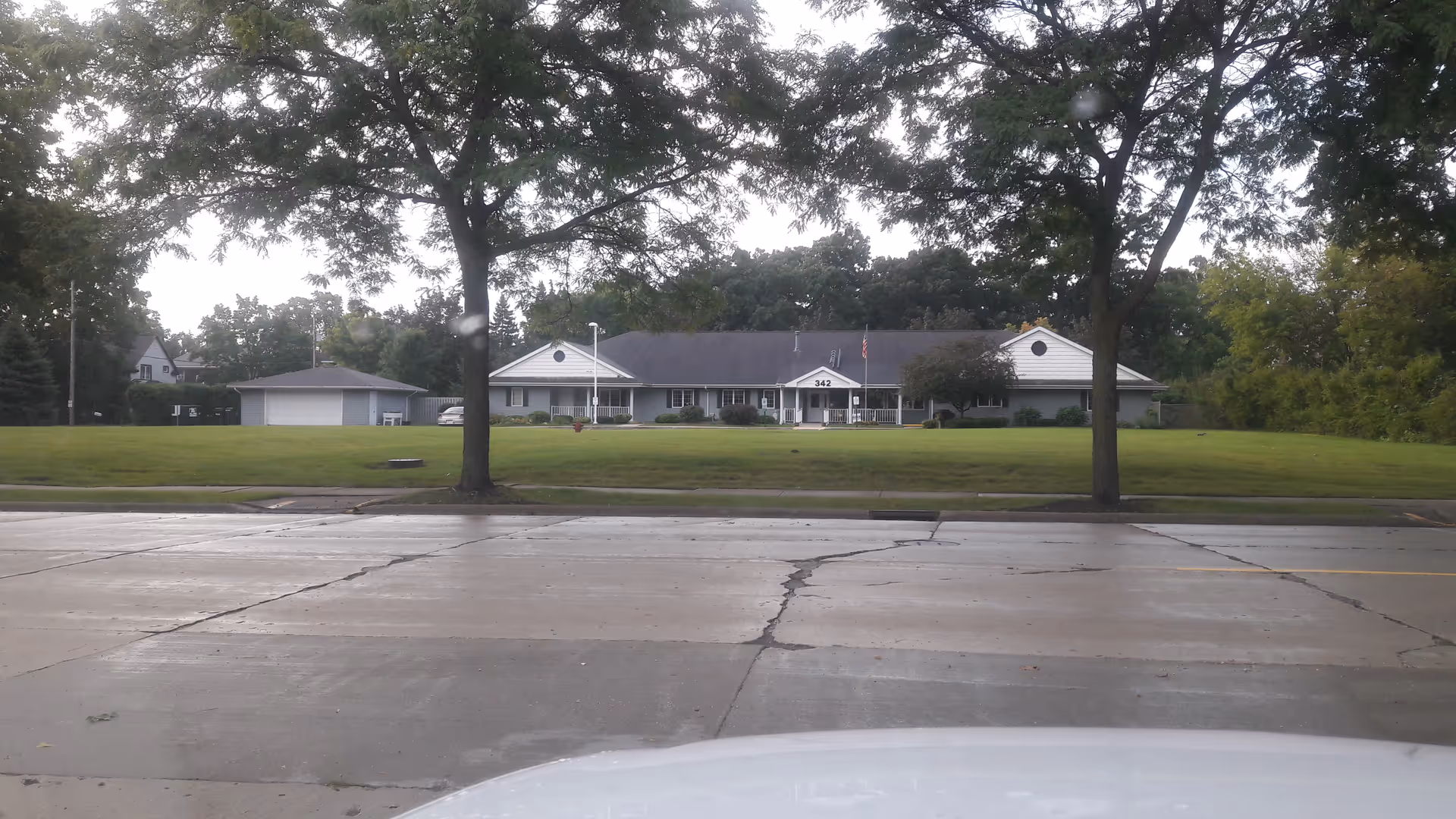 Front view of Lincoln House senior living facility with expansive lawn and large trees