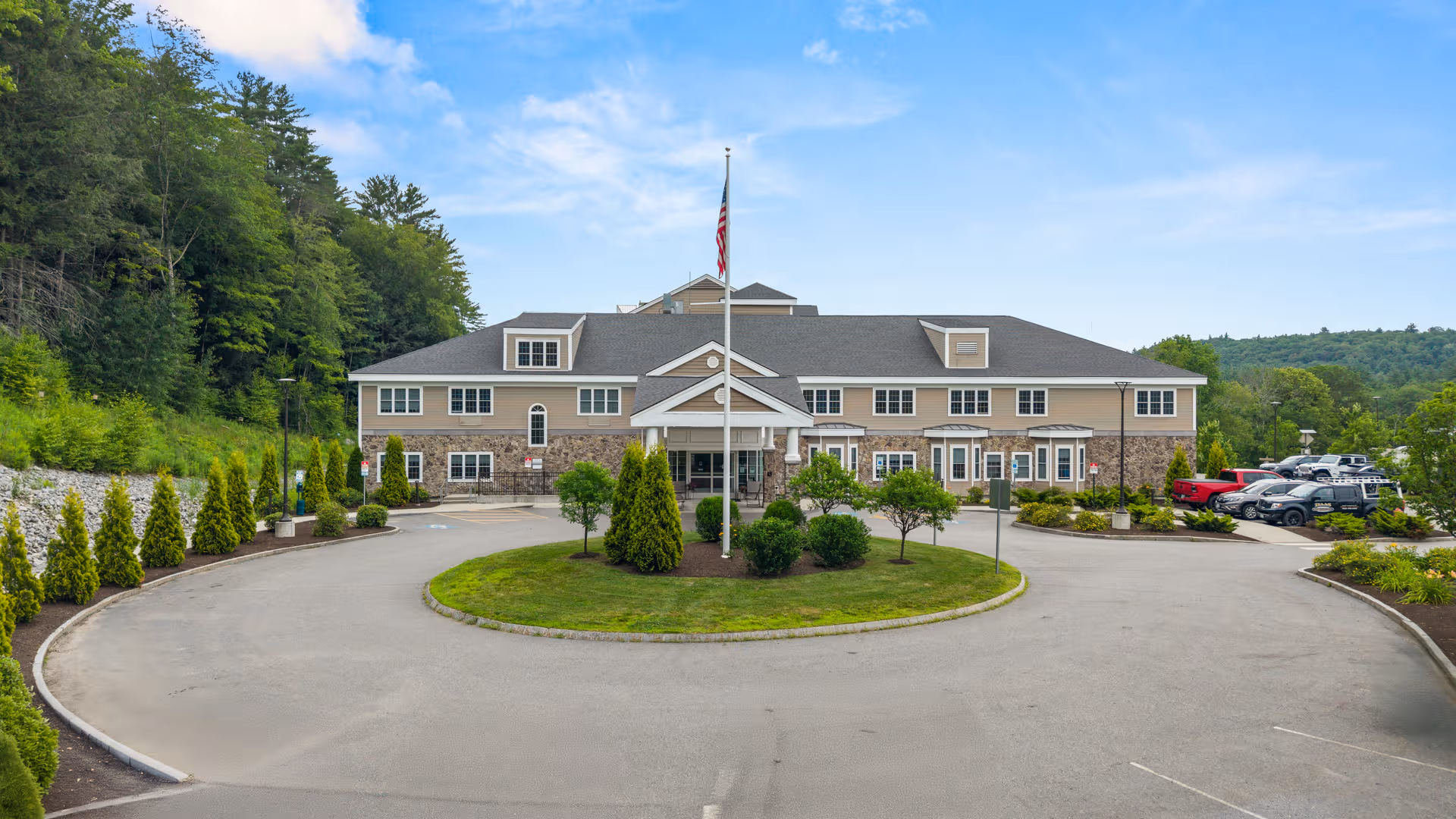 Front view of Covenant Living of Keene facility with circular driveway and flagpole.