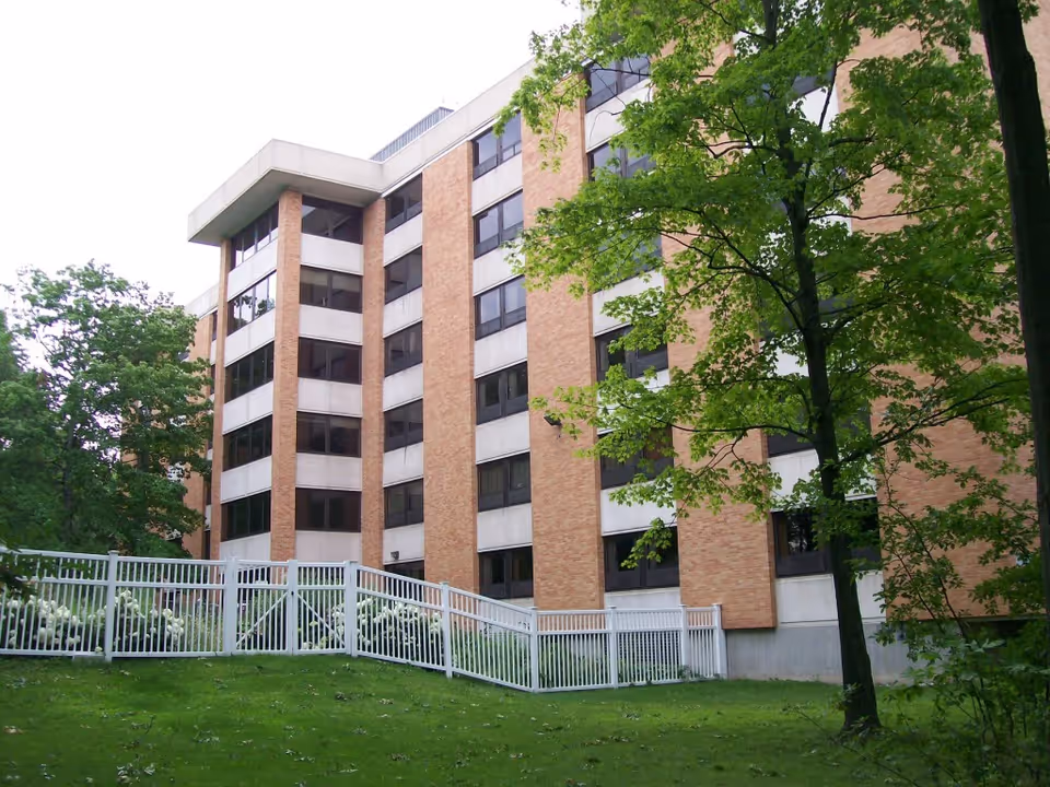 Taylor Park Senior Apartments building on a grassy, tree-lined exterior with a white fence.