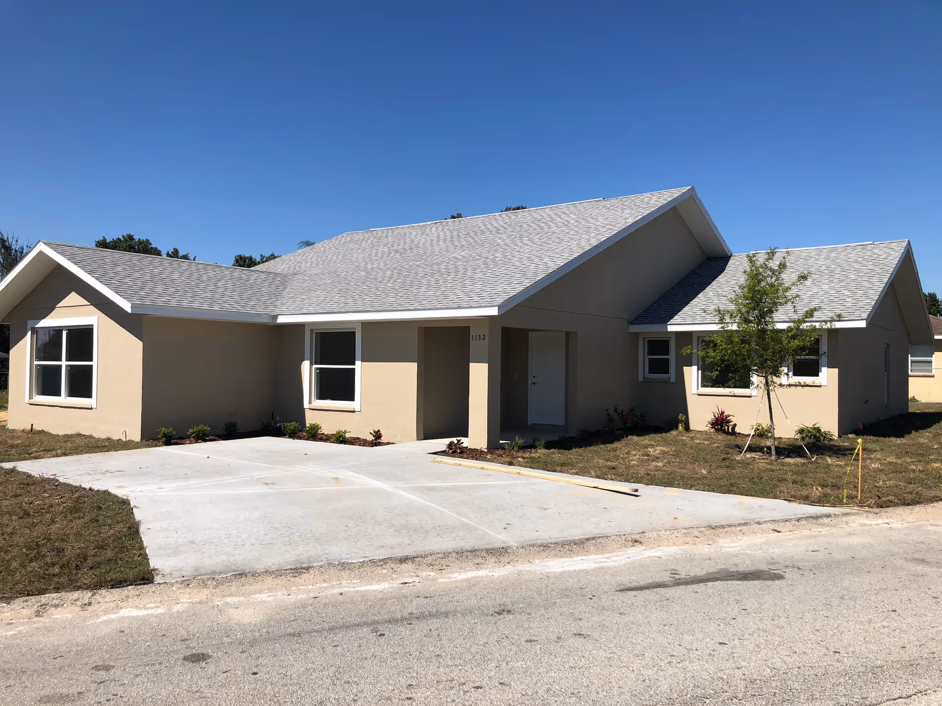 A single-story beige senior living facility with a driveway and blue sky.