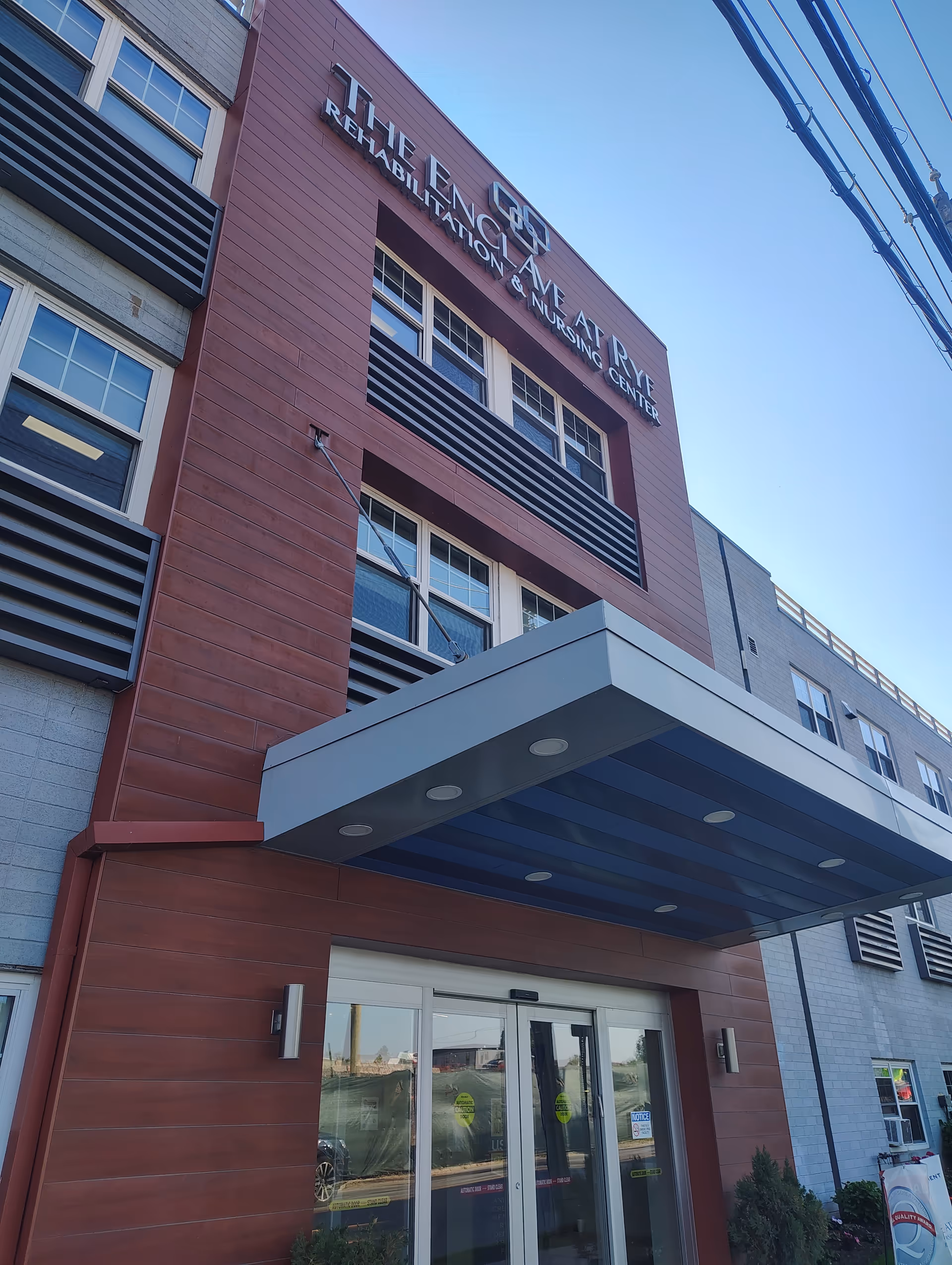 Front facade of The Enclave at Rye Rehabilitation and Nursing Center with a blue canopy.