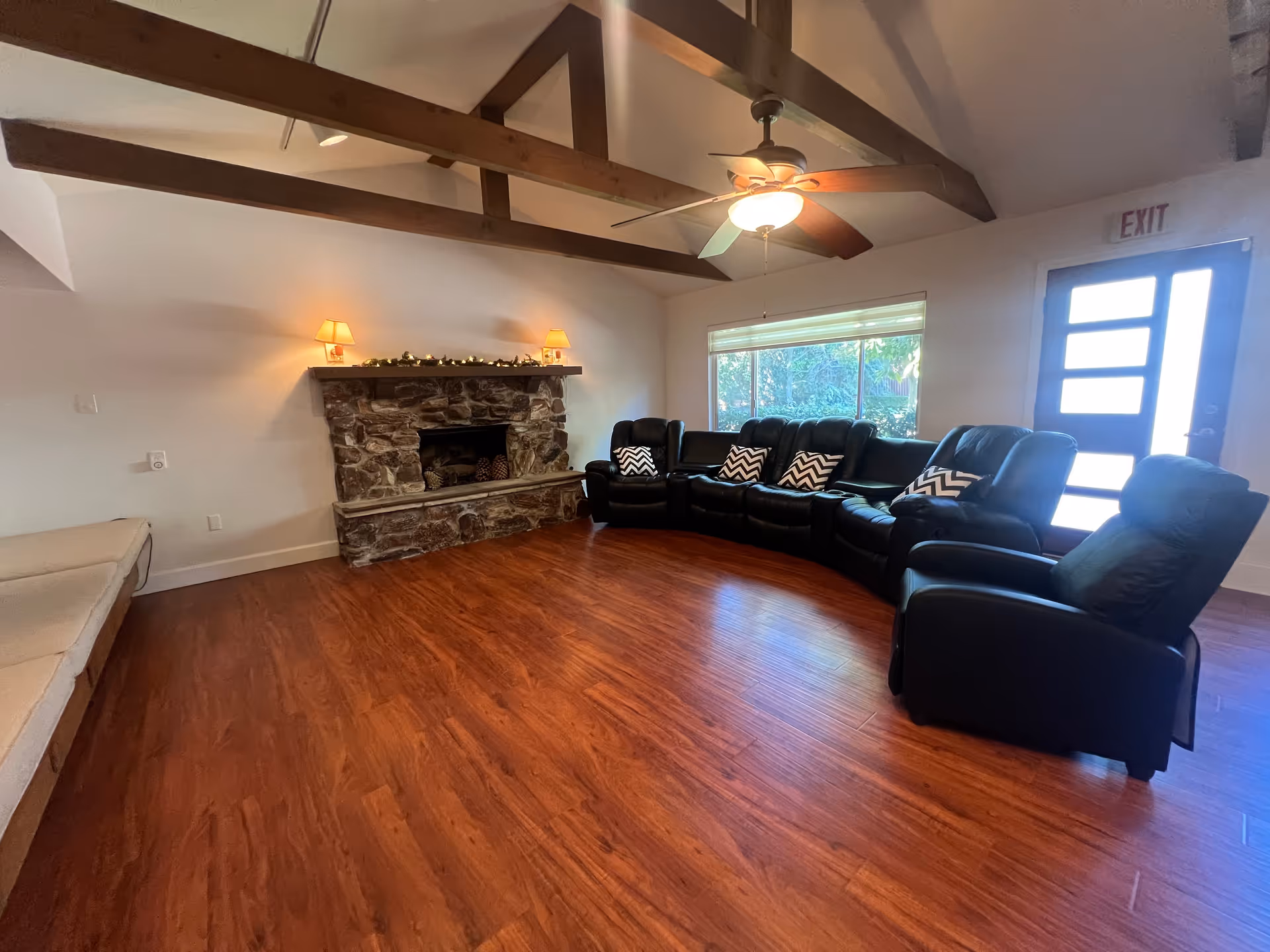 Cozy communal living room with a stone fireplace and curved black leather seating.