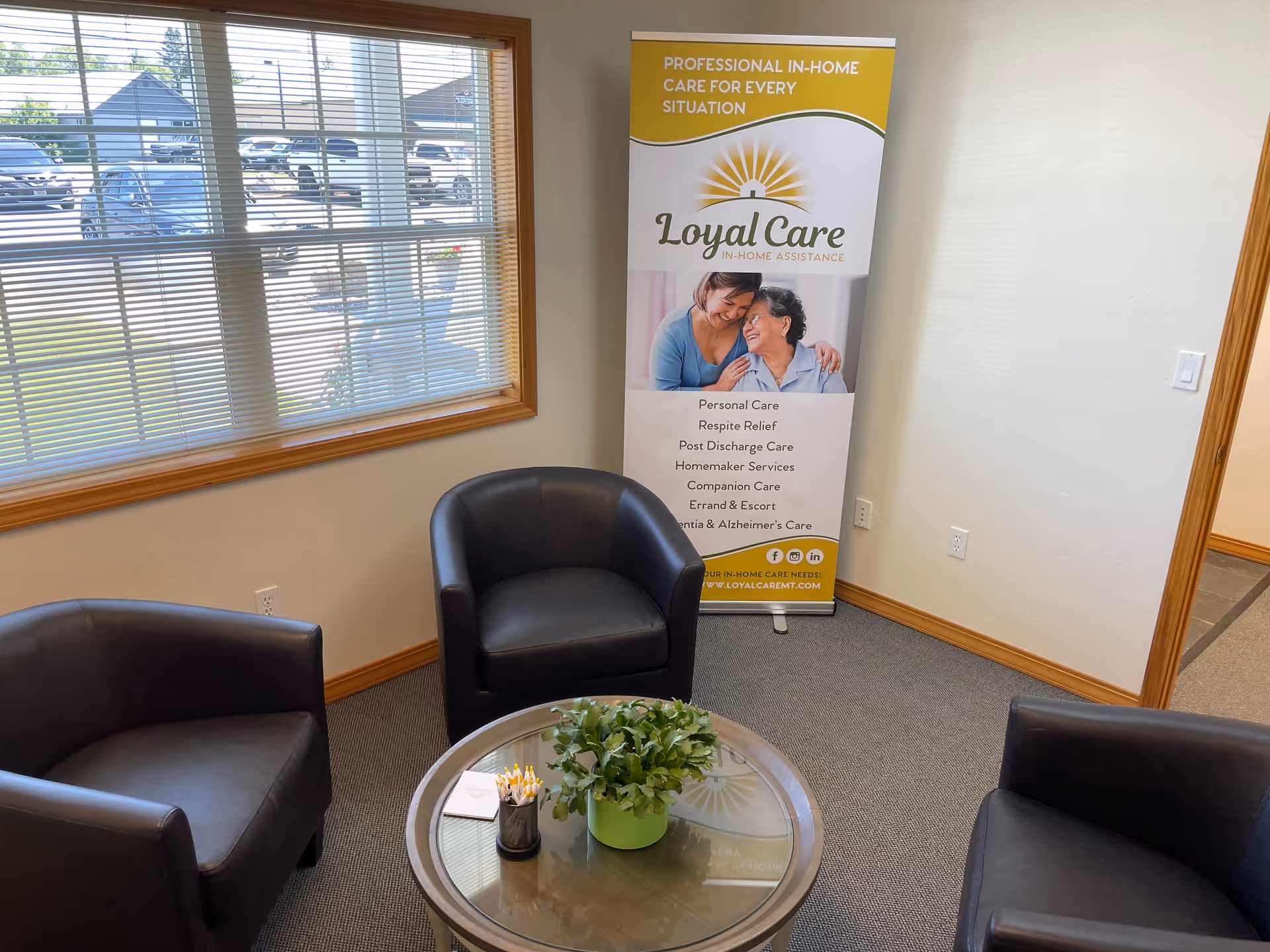 Waiting area with three black chairs, glass table, and a Loyal Care banner.