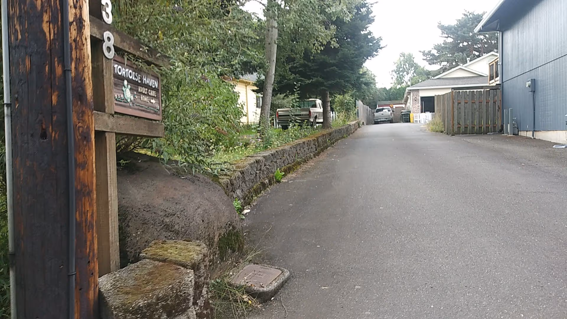 Paved driveway leading to a building with Tortoise Haven Adult Care Home sign on the left.