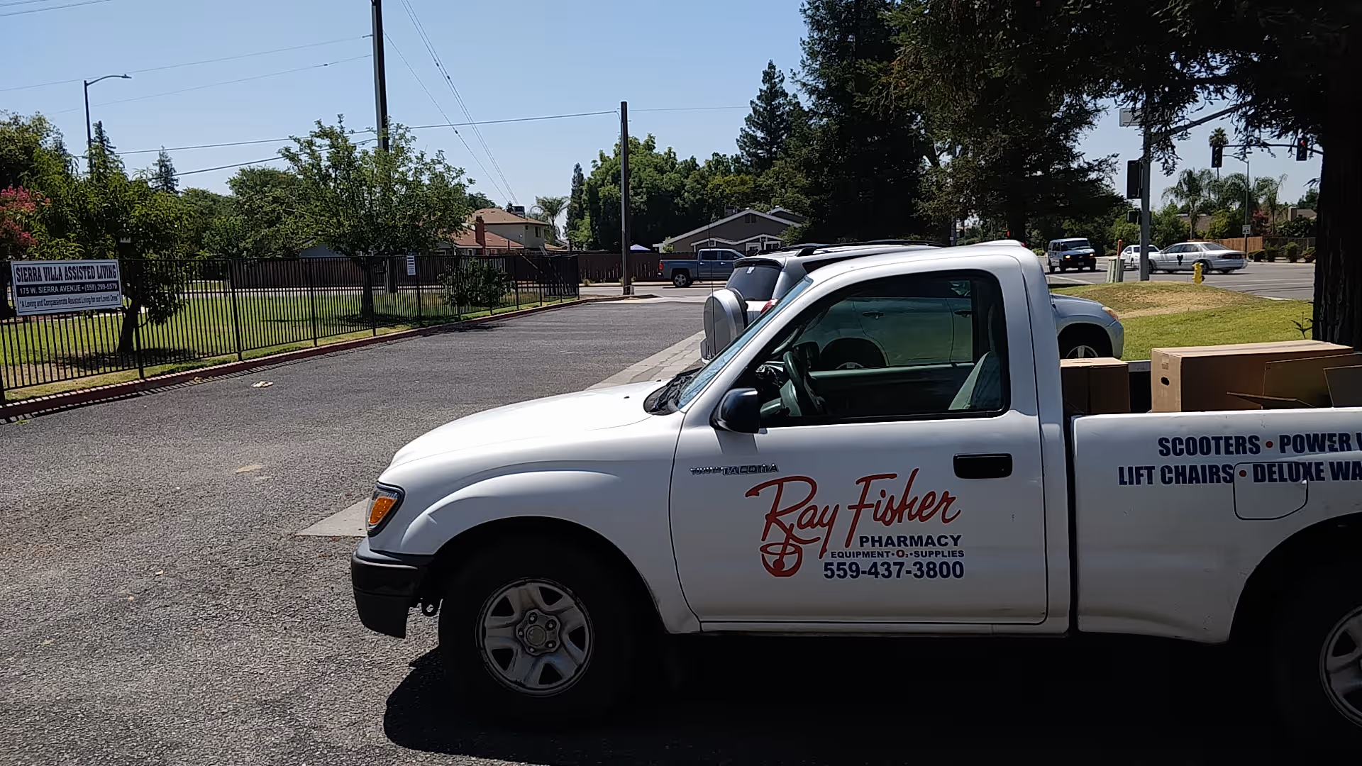 White pickup truck parked outside Sierra Villa Assisted Living with a fence and sign.
