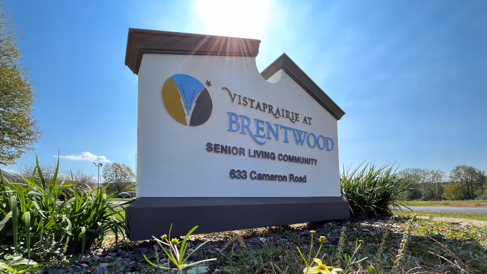 Exterior view of Vista Prairie at Brentwood sign with landscaping and blue sky.