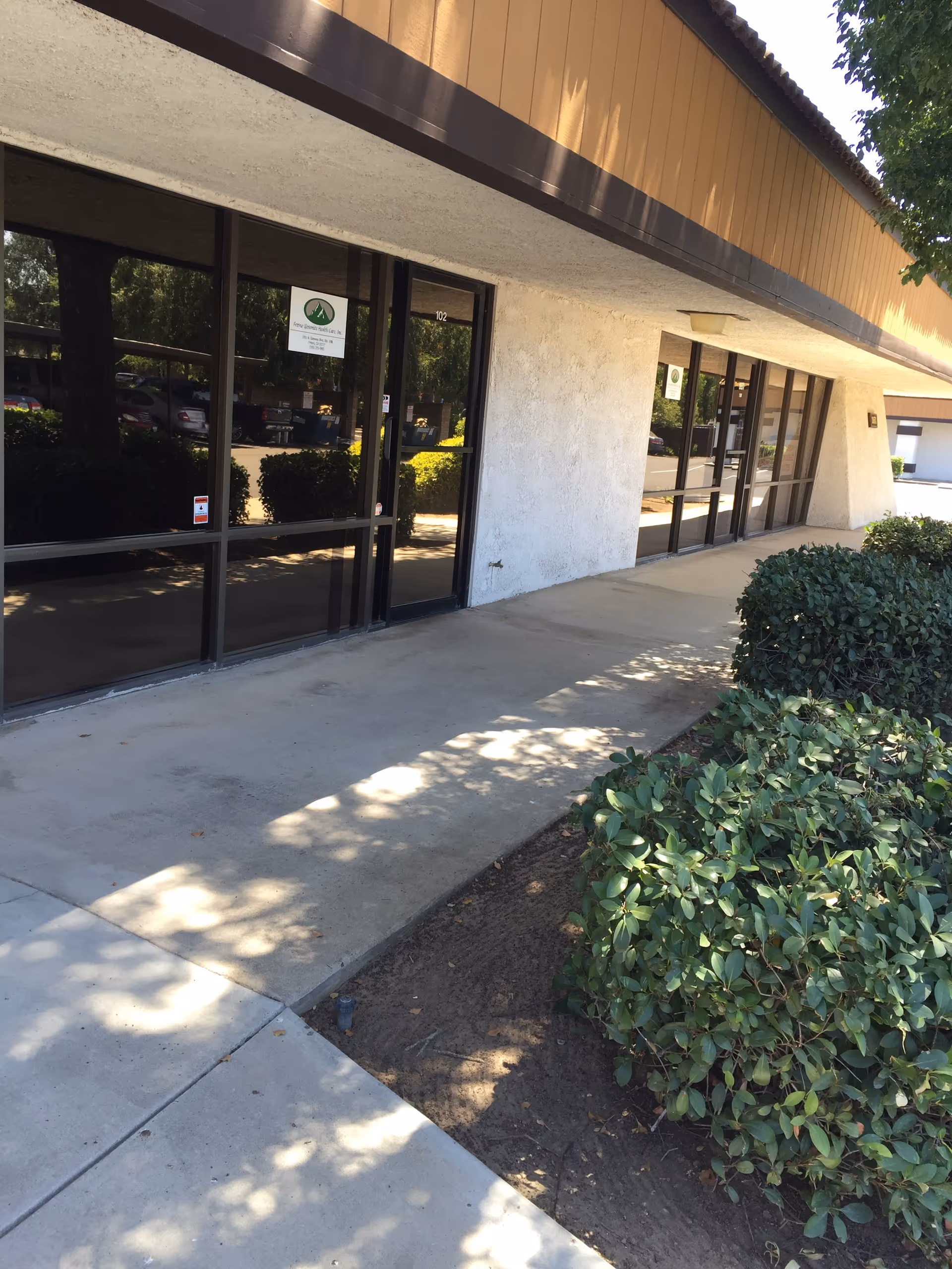 Exterior view of Fresno Yosemite Health Care facility with glass doors and landscaped walkway.