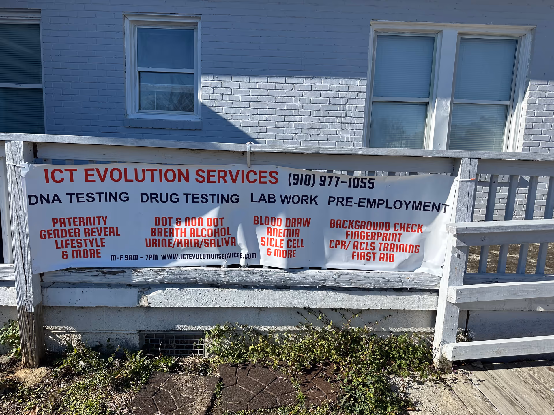 Banner advertising ICT Evolution Services on a white railing in front of a blue brick building