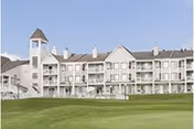 Alder House senior living building with balconies and a large green lawn in front.