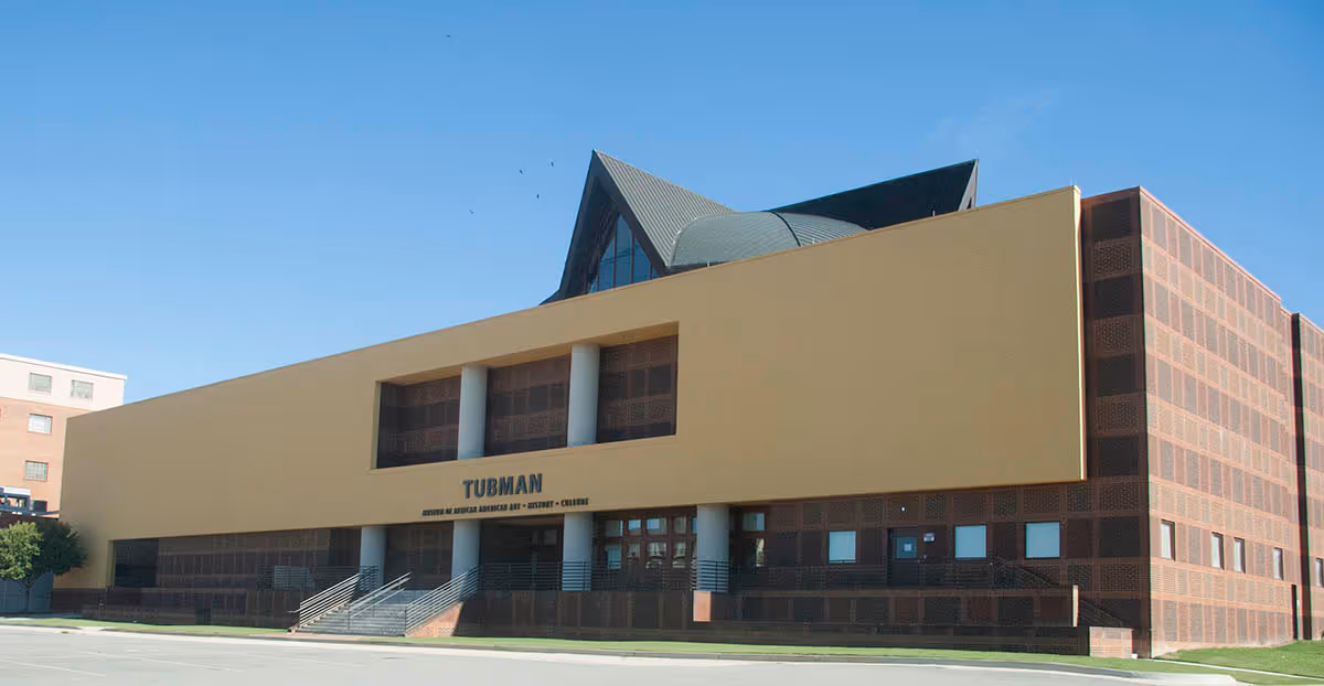 Modern beige-brick building exterior with a prominent entrance and stairs.