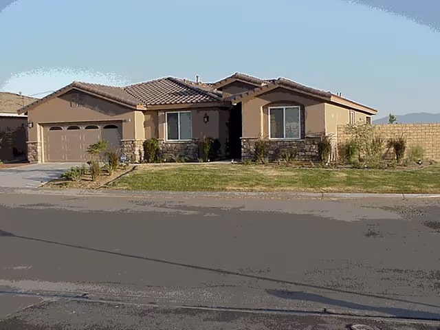 Front view of Desert Cottages I: a single-story beige senior living home with landscaping.