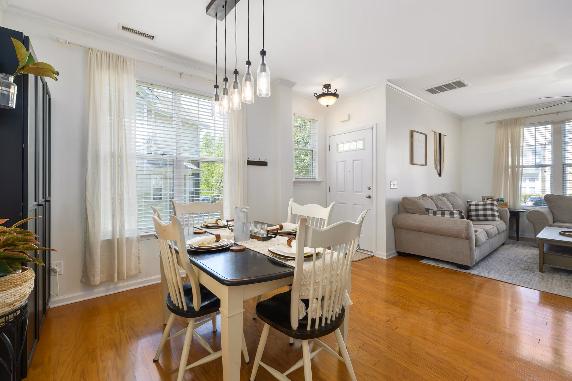 Bright dining area with a table set for meals adjacent to a living room.