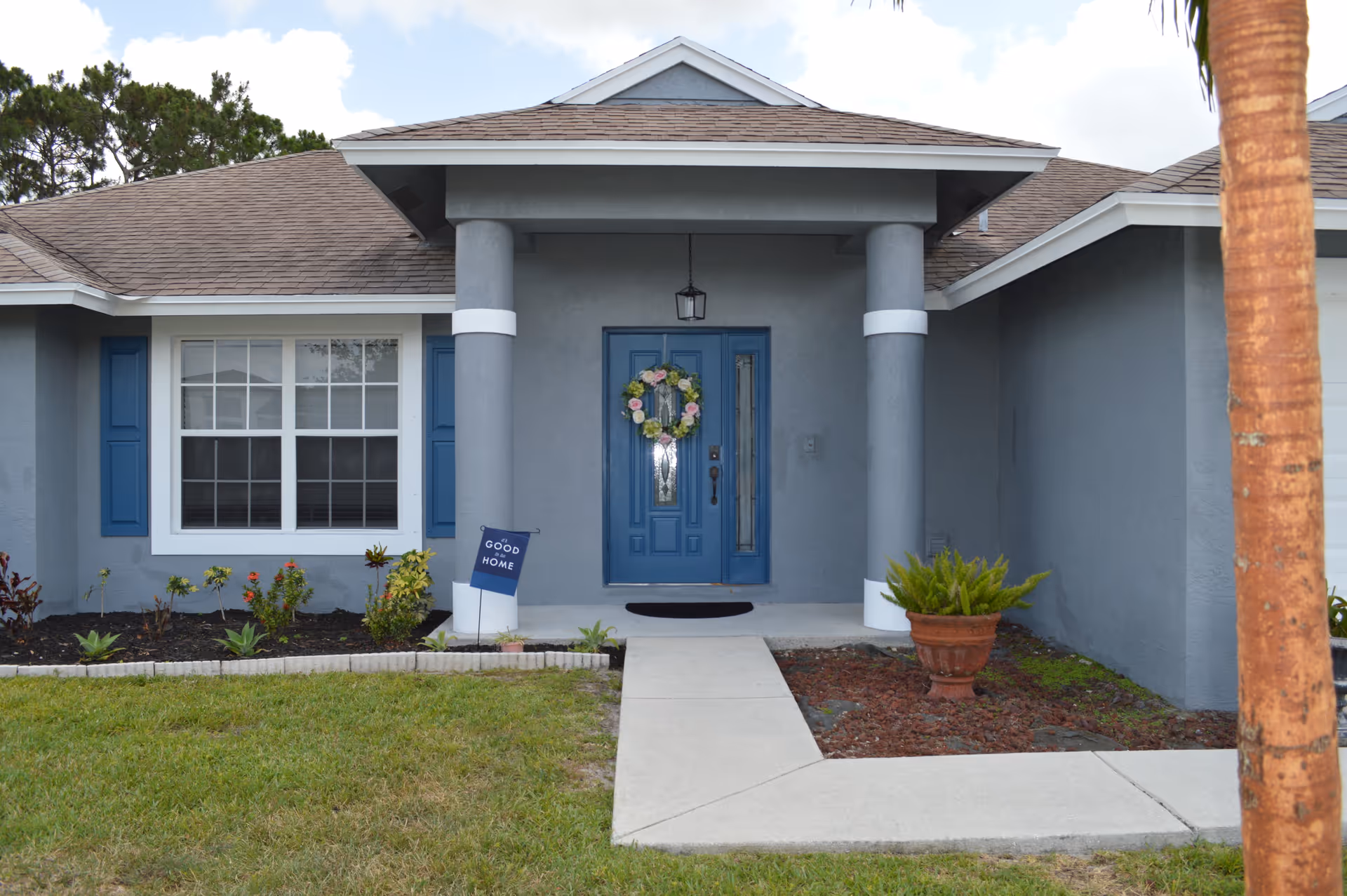 Blue-gray front of a senior care facility with wreath on the door and porch pillars.