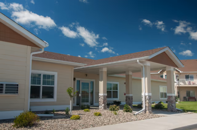 Exterior view of Temperance Lake Ridge Senior Living with a covered entrance and blue sky.