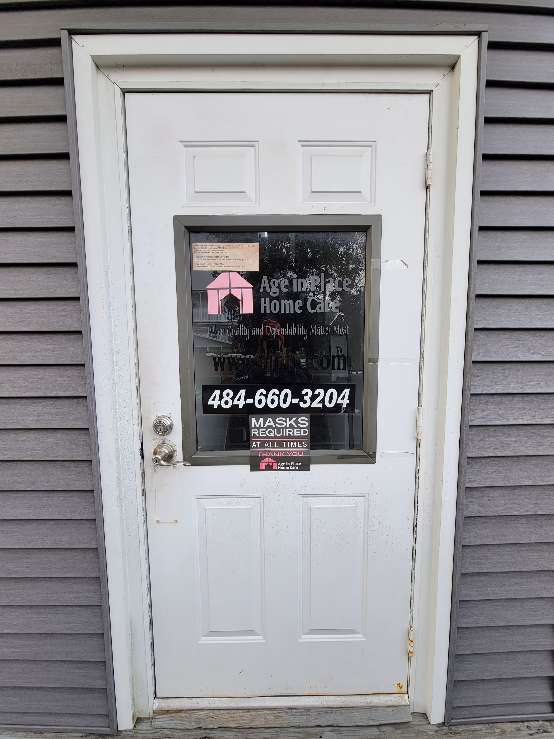 White front door with Age In Place Home Care Hamburg signage on gray siding
