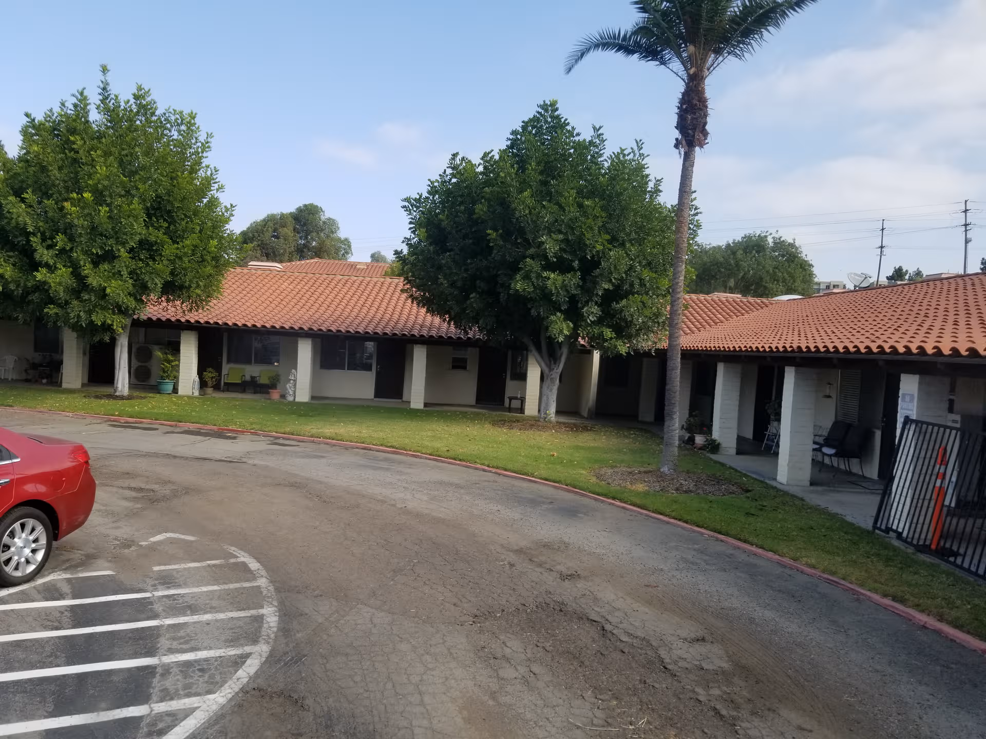 Nazareth House exterior: single-story building with red-tiled roof, covered walkways, trees, and curved driveway.