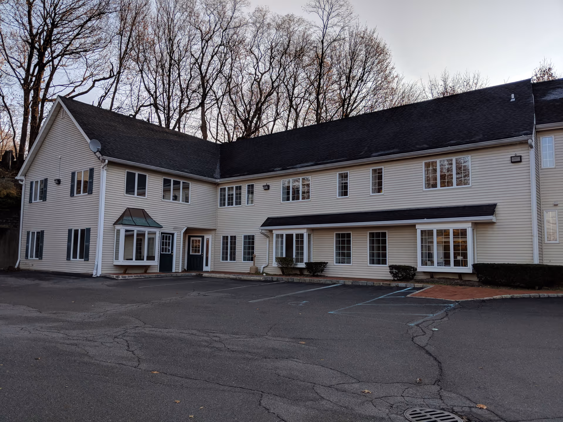 Exterior view of a two-story beige senior living building with windows and parked lot