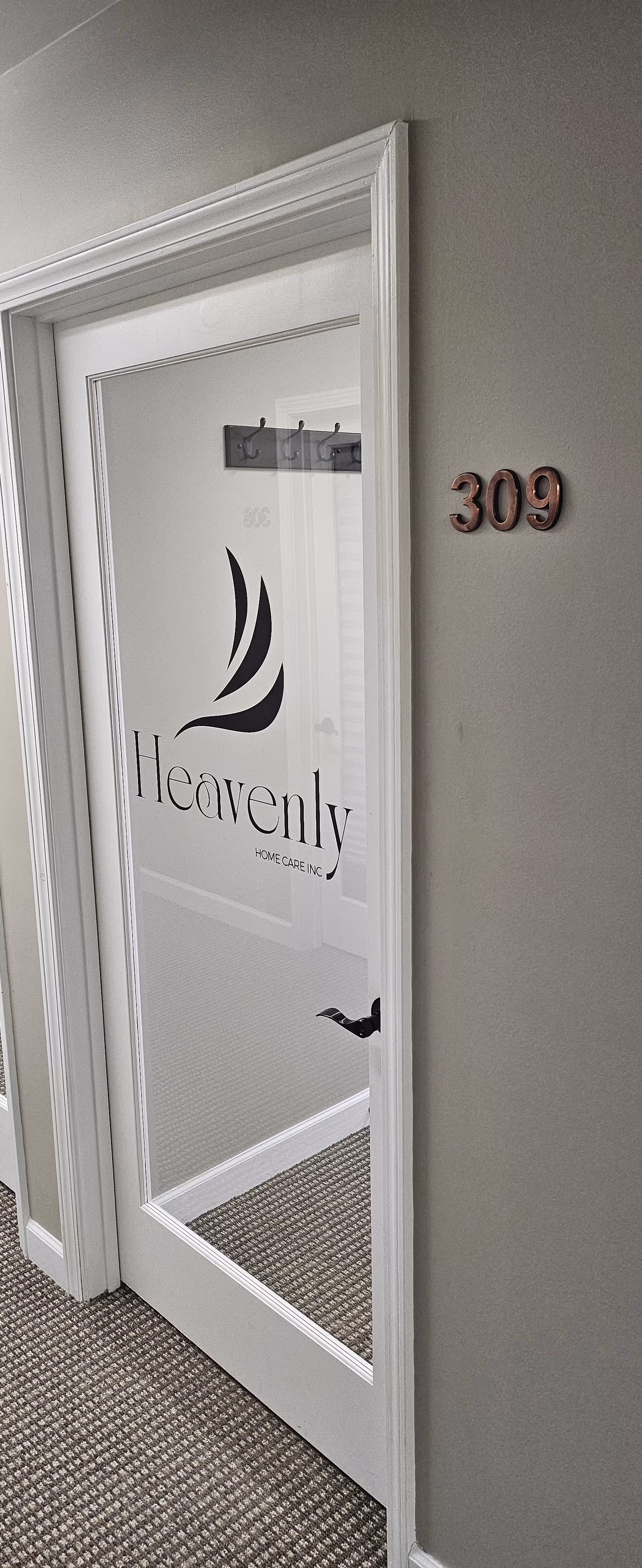 Indoor hallway with a glass-paned door displaying Heavenly Home Care Inc. and unit 309.