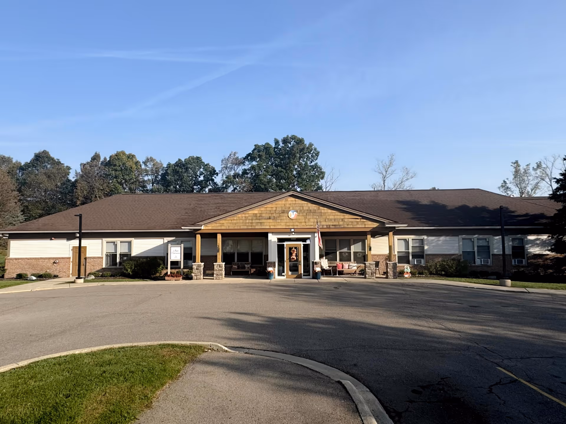 Single-story senior living facility exterior with a central entrance and parking lot.