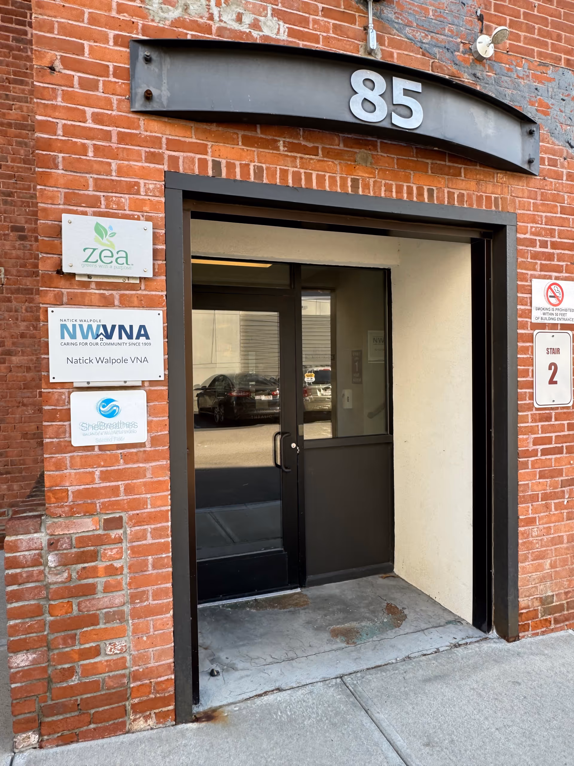 Brick building front entrance with a black door and the number 85.