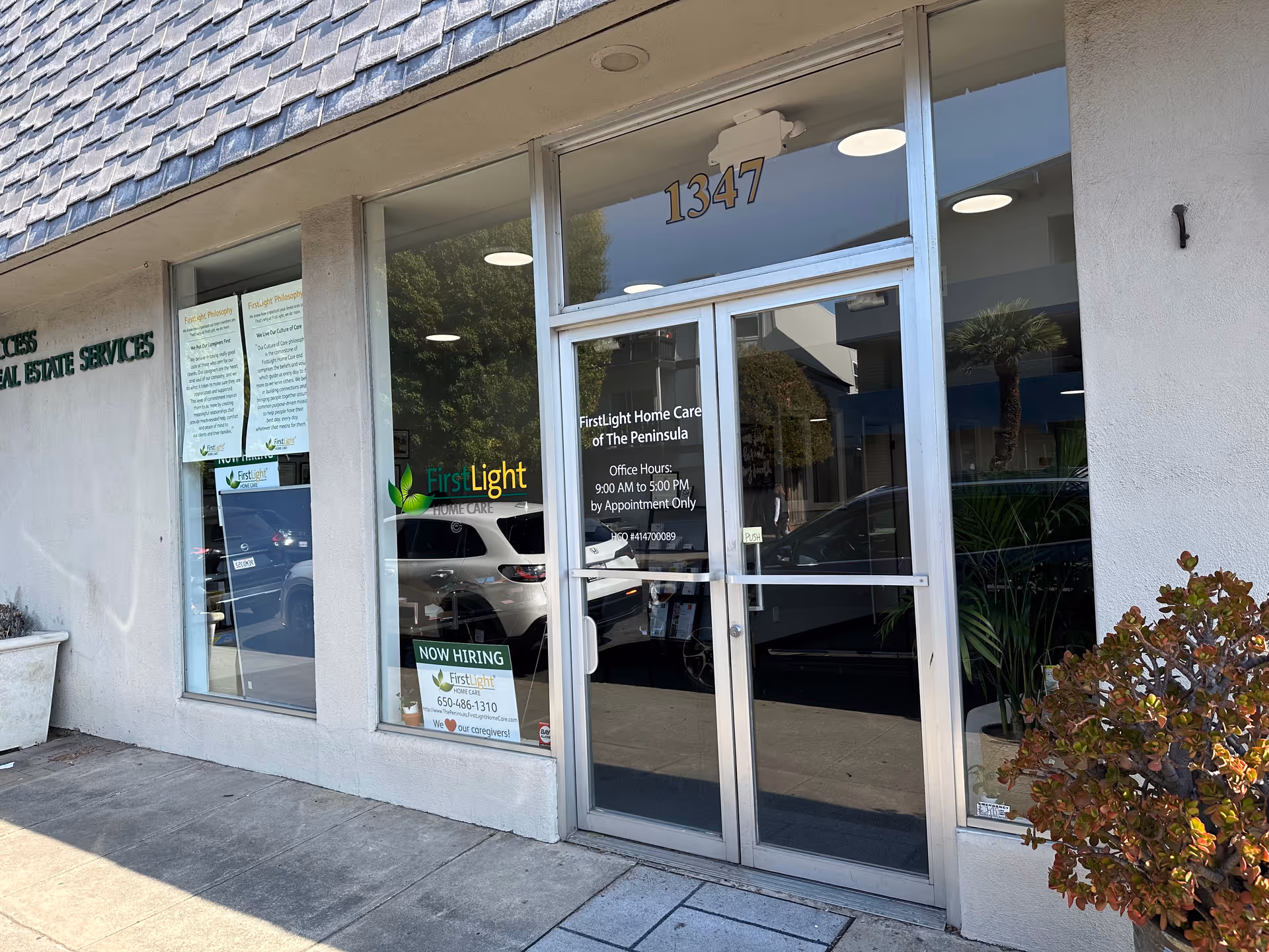 Storefront entrance with glass doors labeled FirstLight Home Care, 1347, and Now Hiring sign visible.