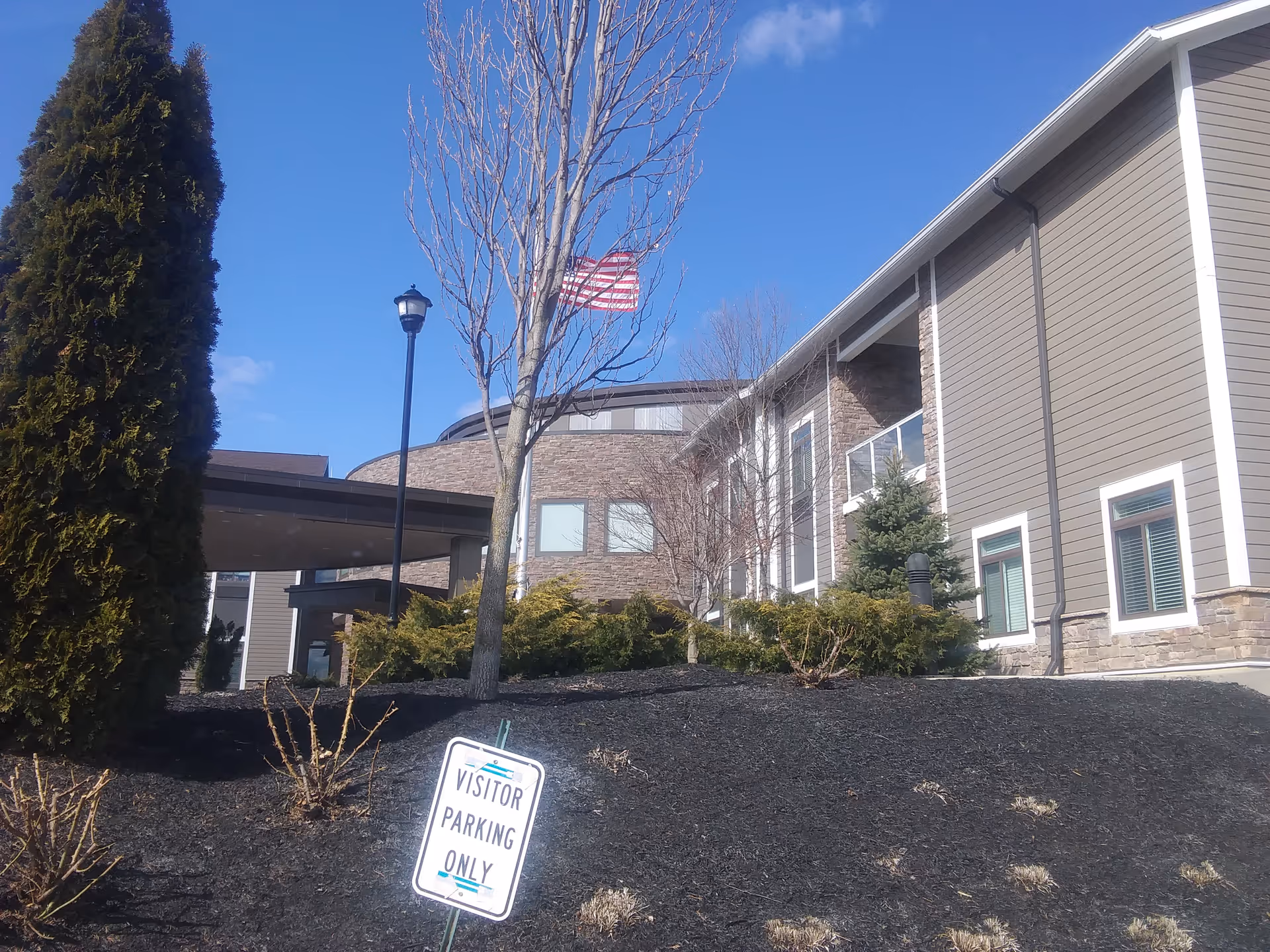 Exterior view of Buffalo Valley Lutheran Village with landscaping, flag, and visitor parking sign.