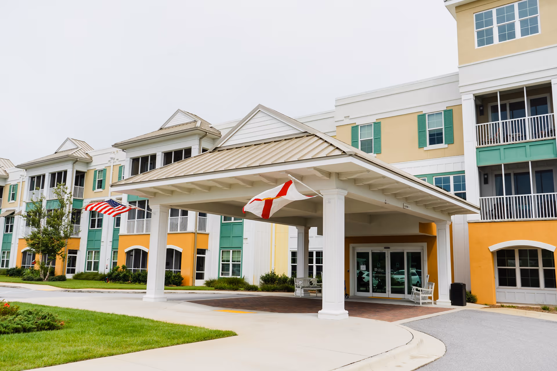 Colorful multi-story senior living facility with a covered entrance and flags