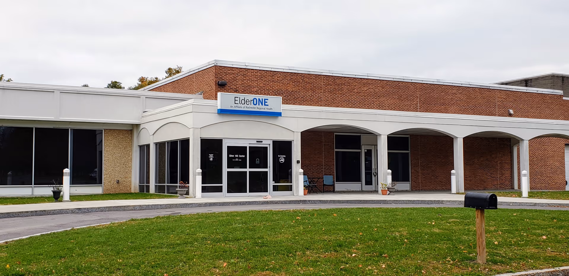 Exterior of ElderONE North Park PACE Center with brick facade, sign, and arched entryways.