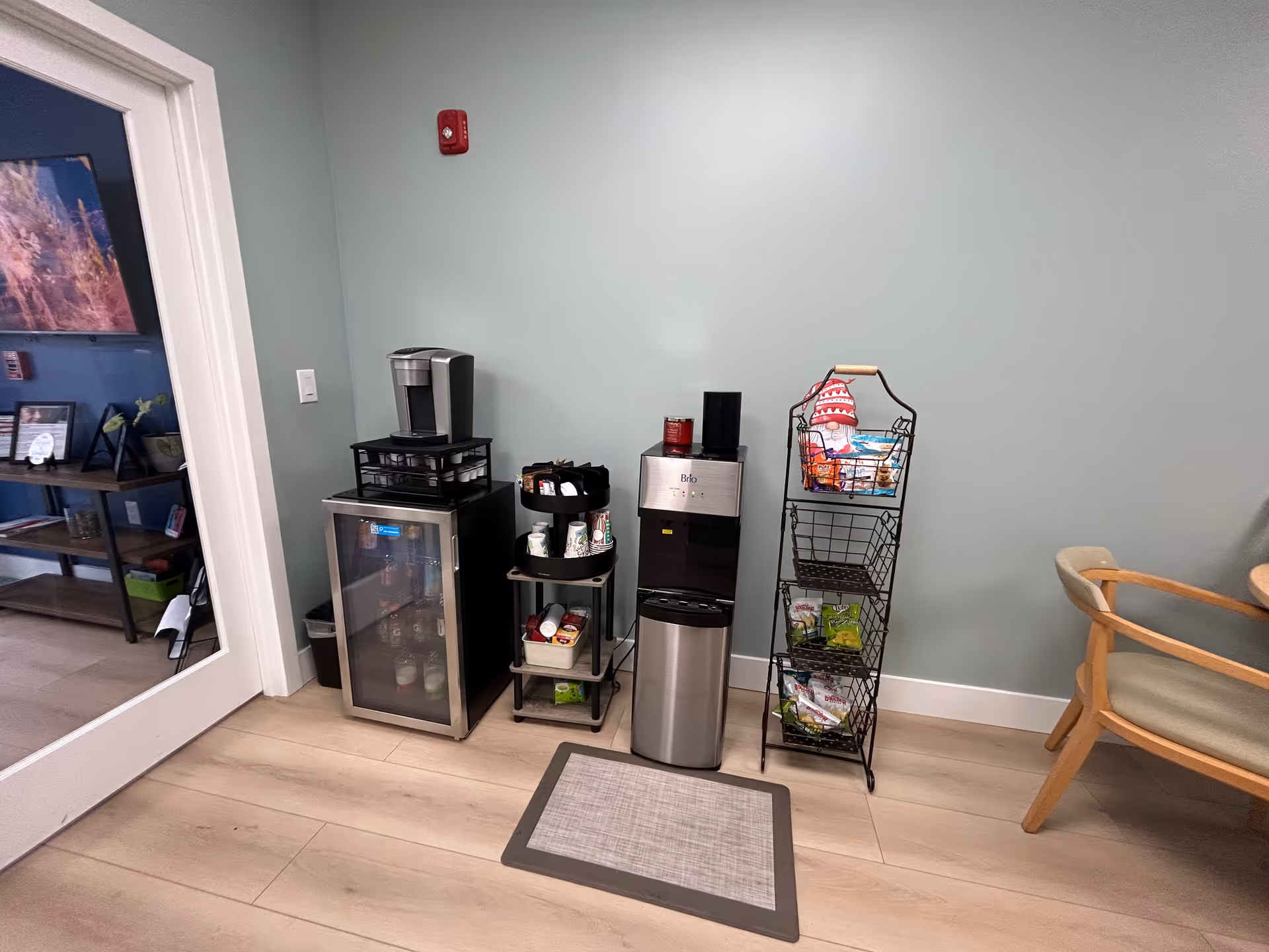Interior break area with coffee station, mini fridge, snack rack, and seating.