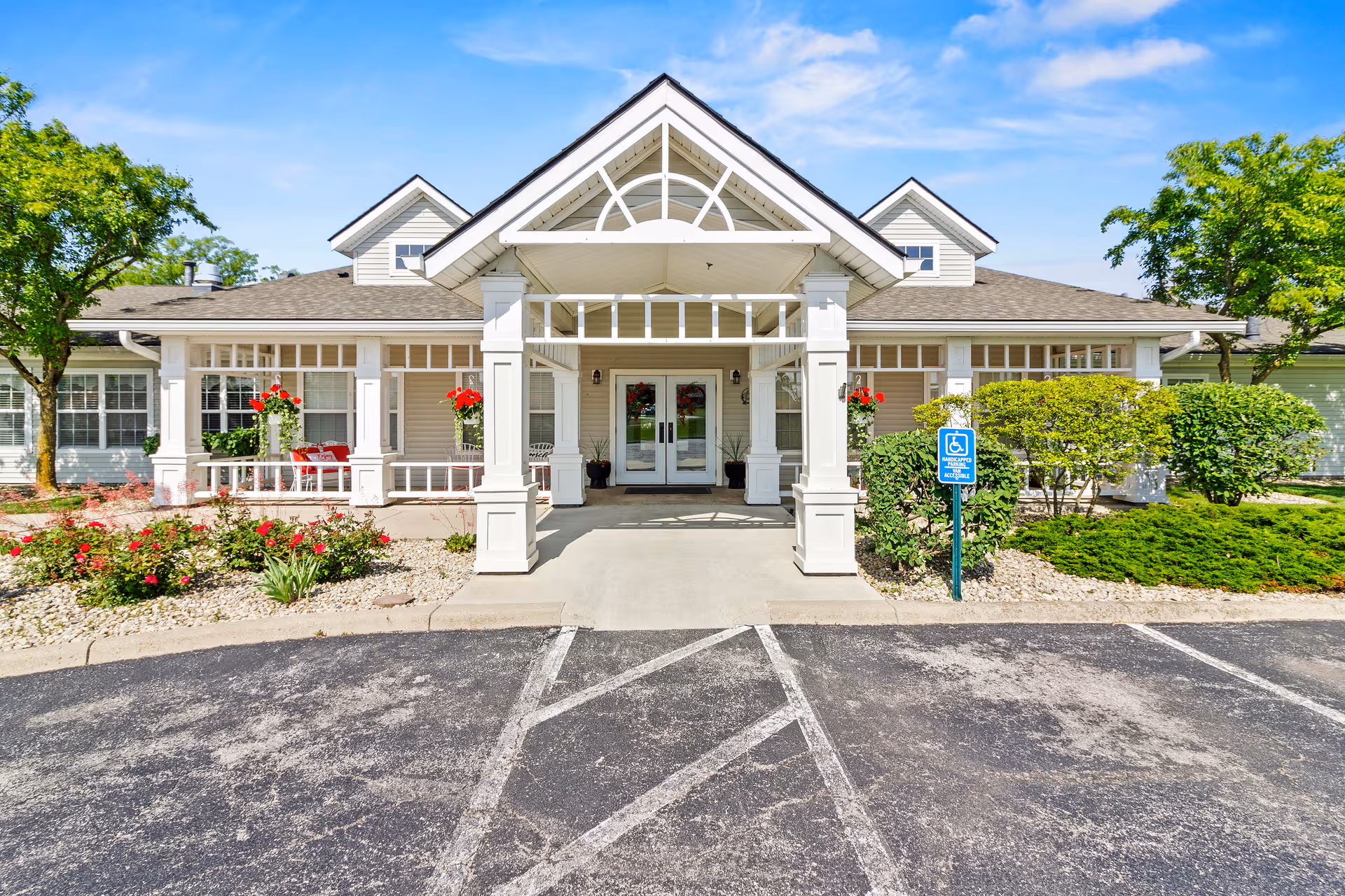 Front view of Taylor Place senior living facility with entry porch, columns, landscaping, and handicap sign.