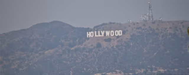 A hilly landscape with a Hollywood sign visible on a distant hillside.