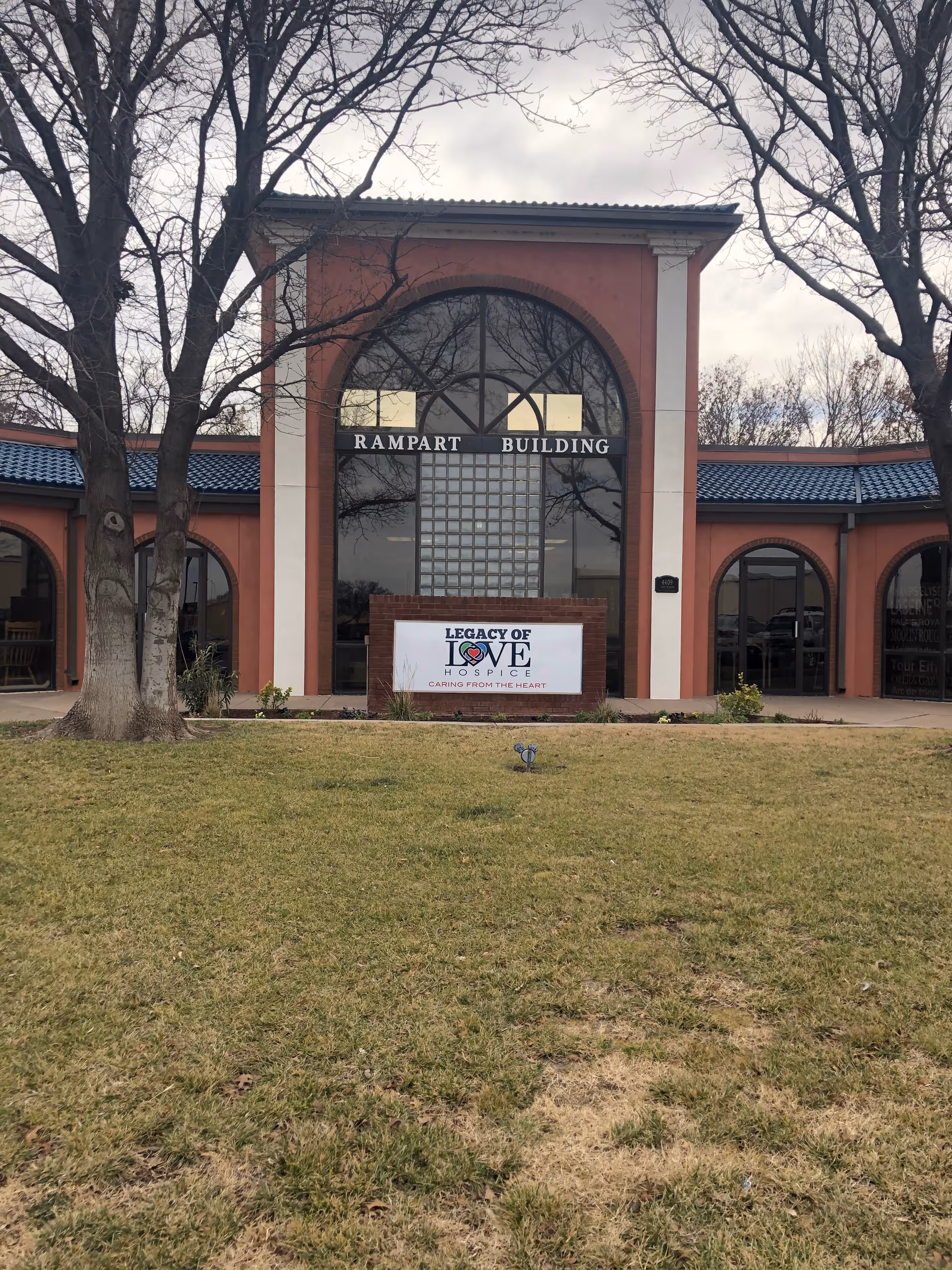 Front exterior of Rampart Building with Legacy of Love Hospice sign and bare trees.