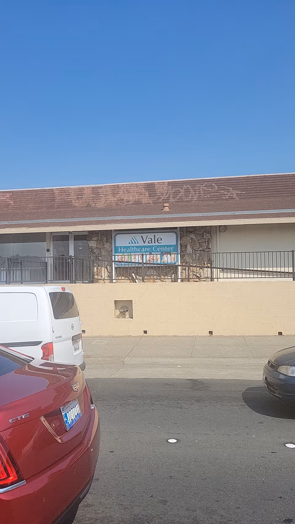 Front exterior of Vale Healthcare Center with a sign and parked cars.
