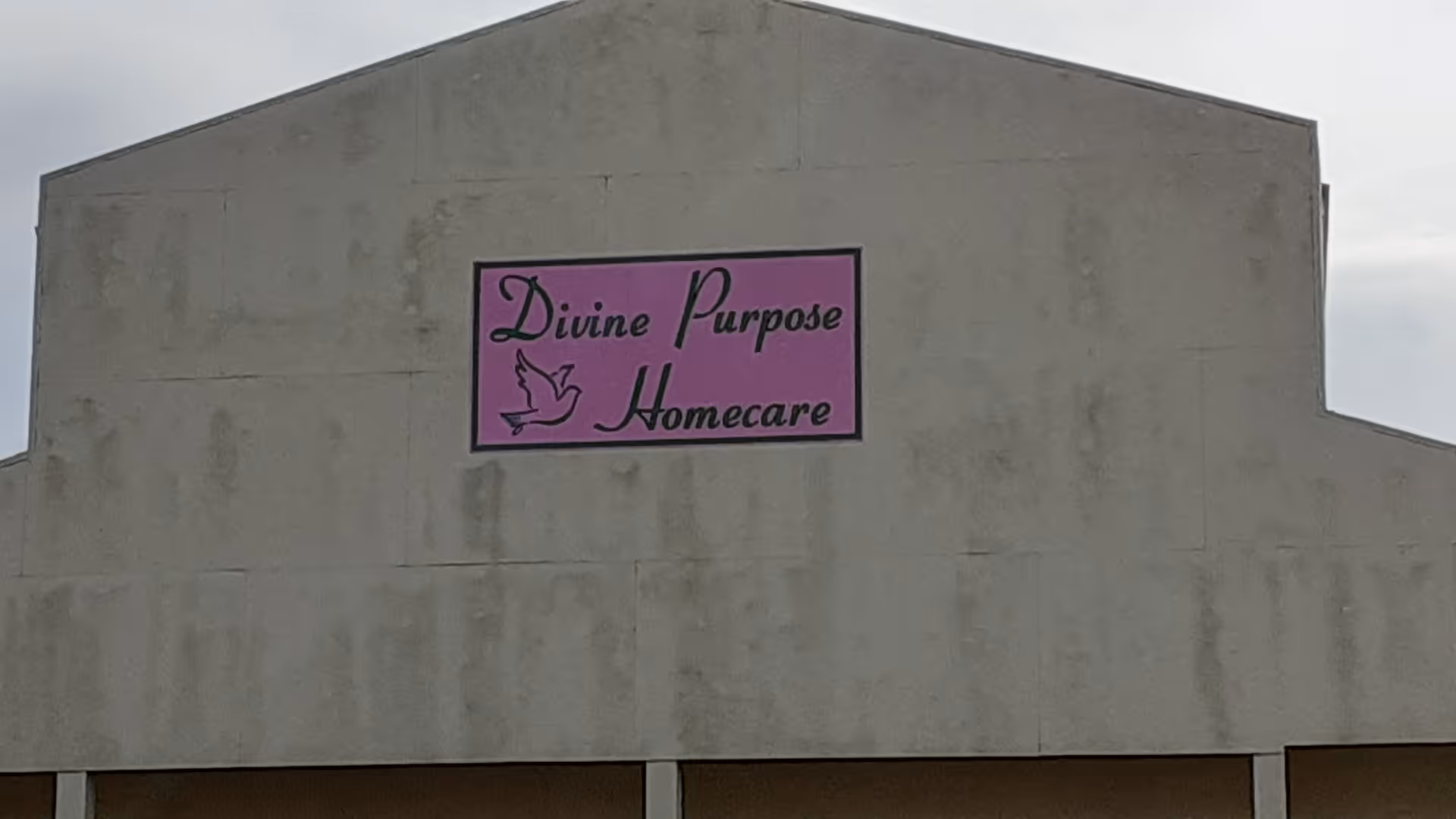 Front of a beige building with a pink Divine Purpose Homecare sign.