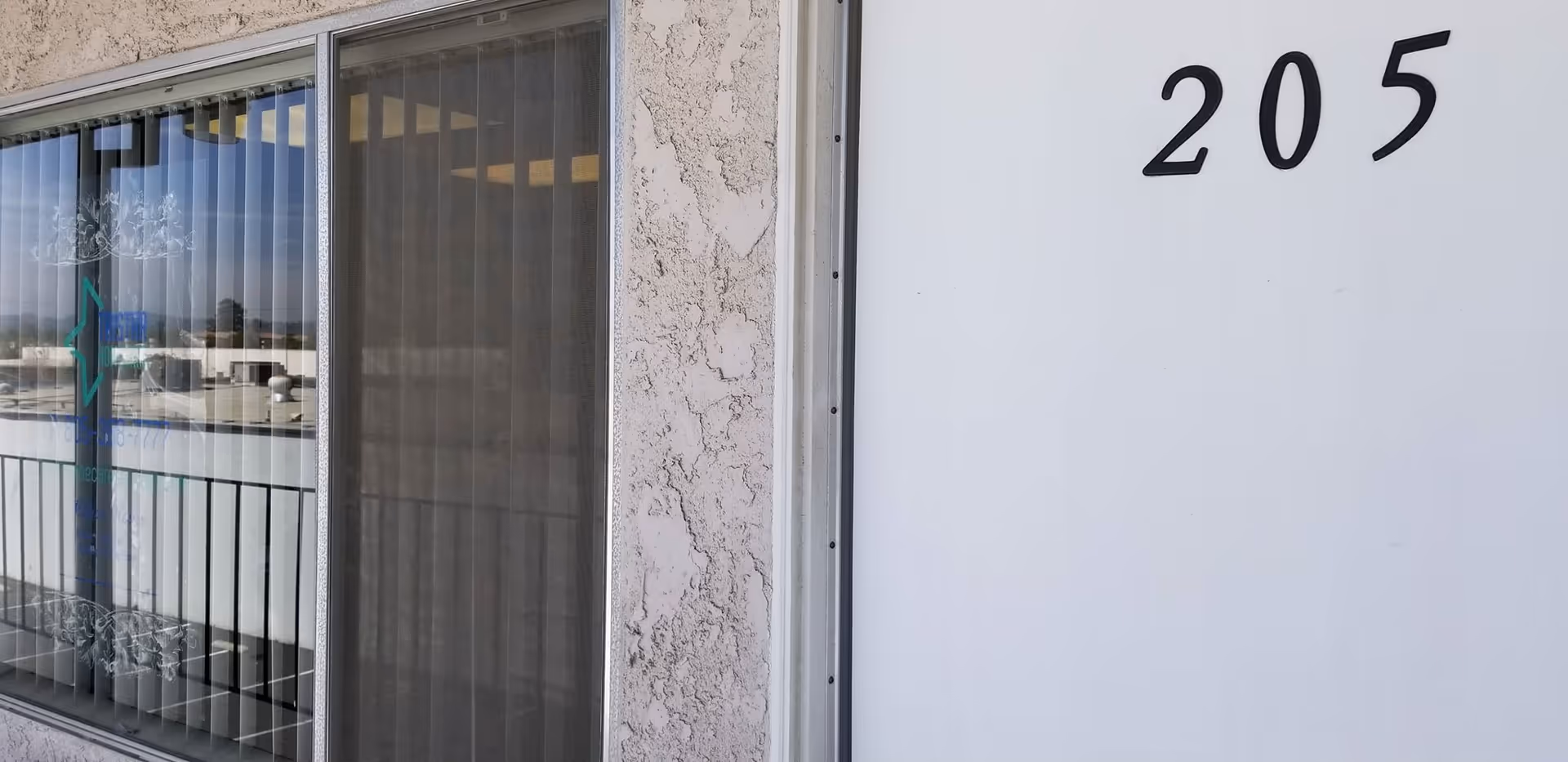 A building exterior with a white door marked 205 and a window.