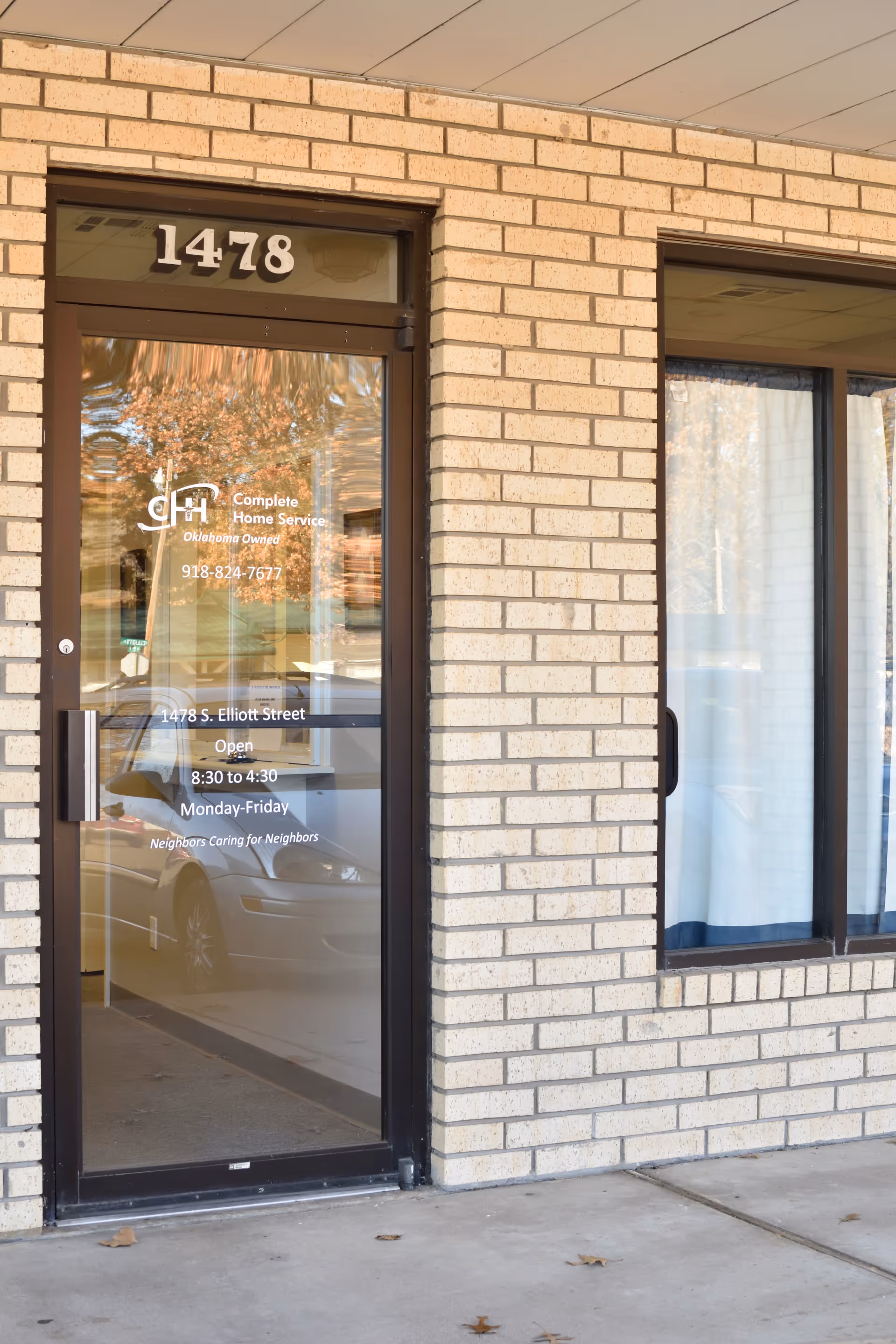 Brick-front building entrance with glass door and Complete Home Service signage.