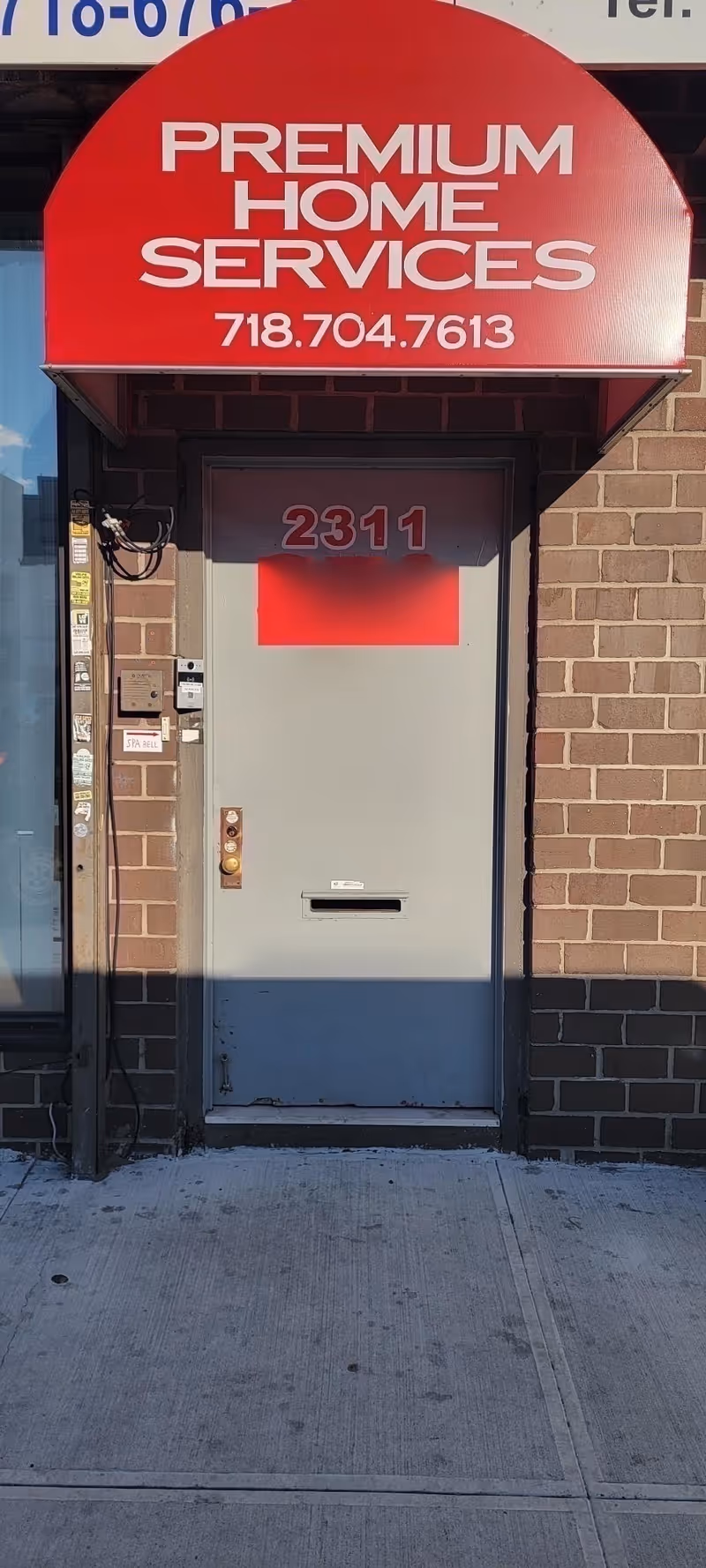 Red curved storefront sign says Premium Home Services above a gray entrance door.