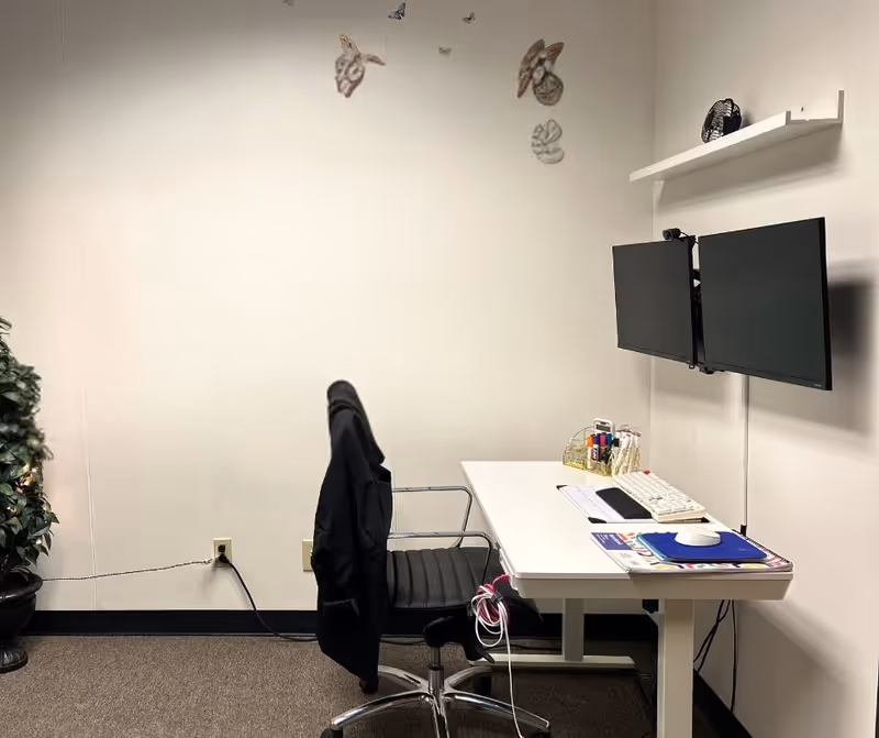 A small office workspace in a senior facility featuring a desk, dual monitors, and a chair.