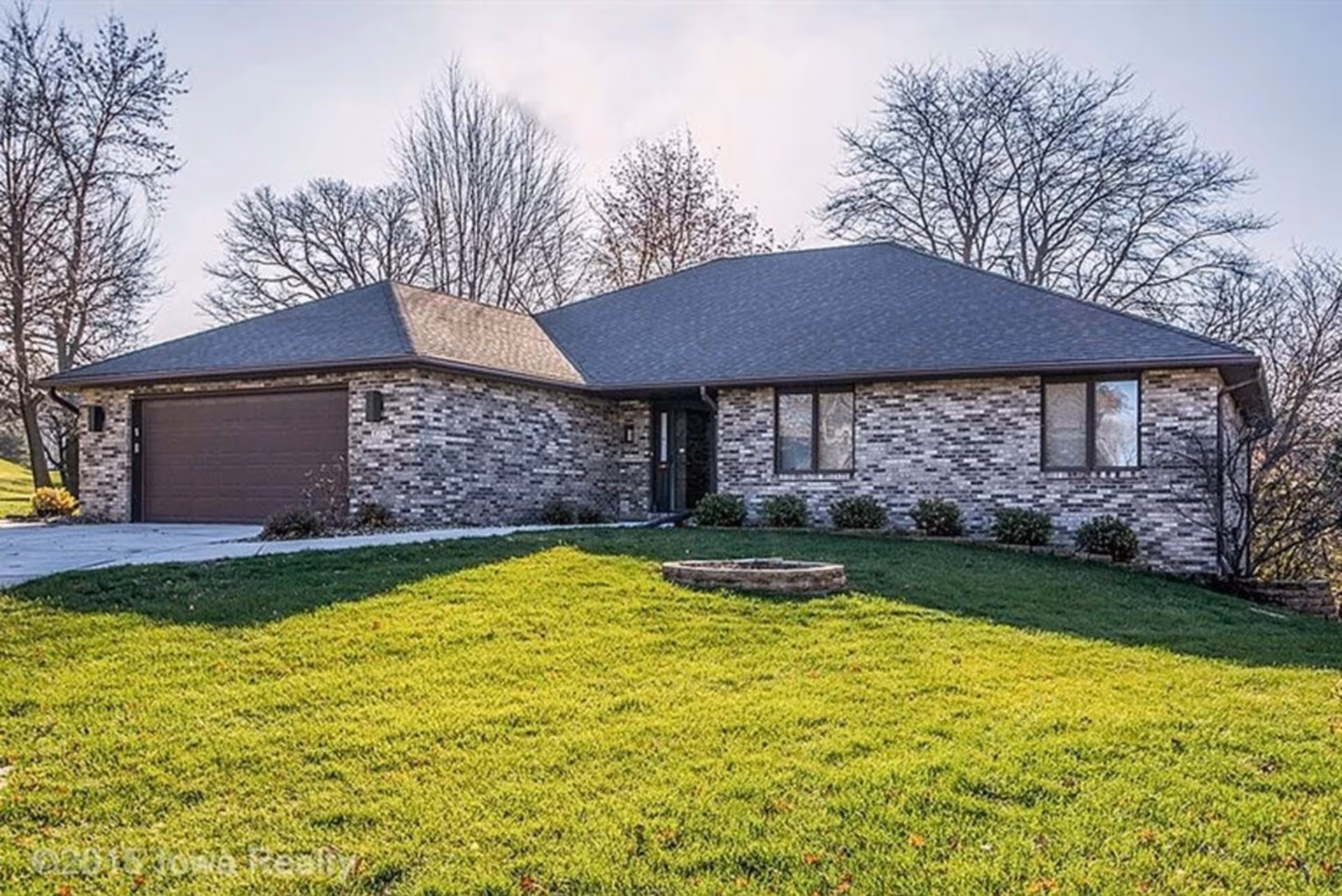 Single-story brick-and-stone house with a manicured lawn and a two-car garage