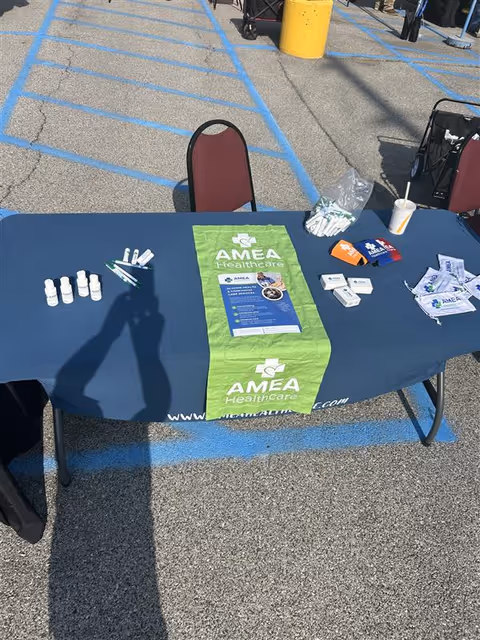 Outdoor promotional table for AMEA Healthcare with brochures and supplies.