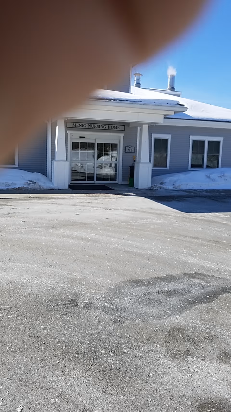 Front entrance of Menig Nursing Home with snow around.
