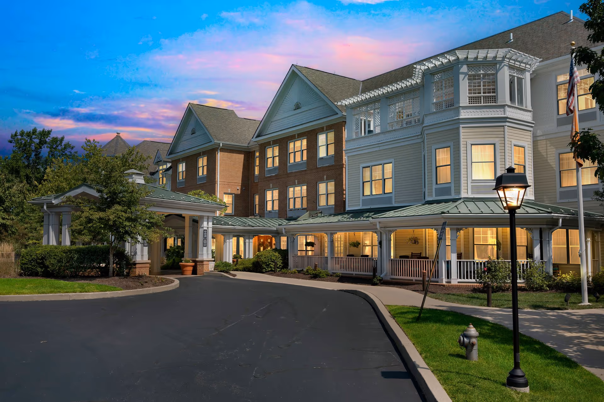 Exterior view of Sunrise of Newtown Square, a multi-story senior living facility with a lit entrance.