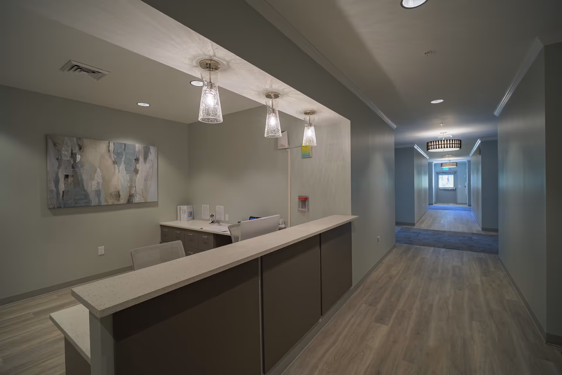 Sunlit reception desk along a long hallway in a senior living facility.