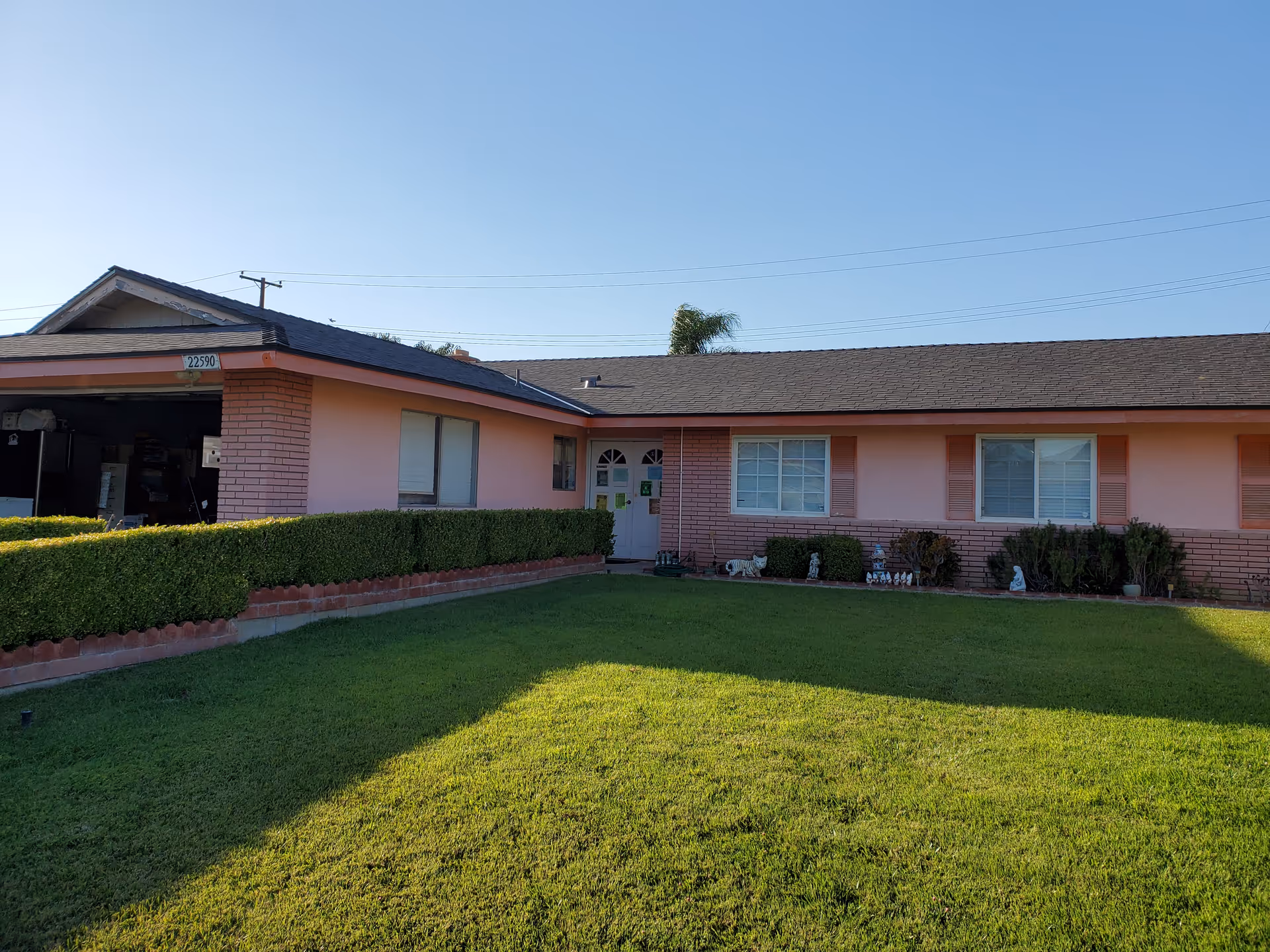 Front exterior of a pink single-story senior living facility with a manicured lawn