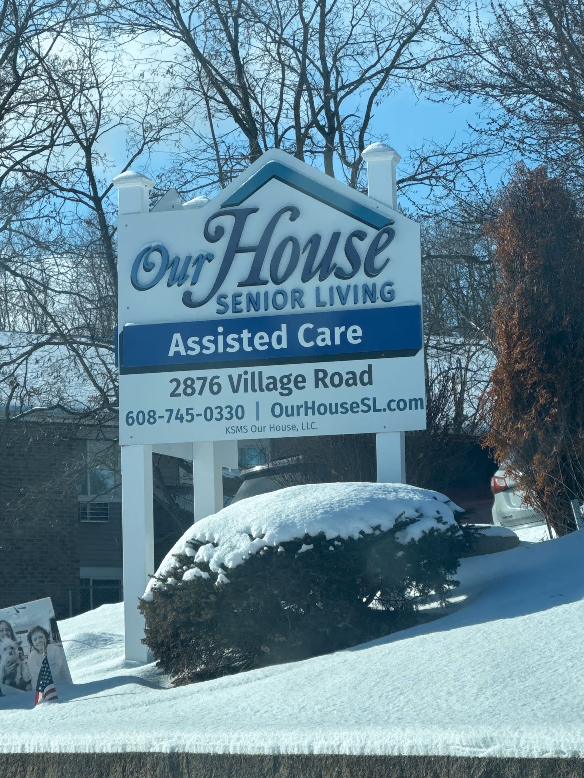 Snow covers the ground around the Our House Senior Living sign outside.