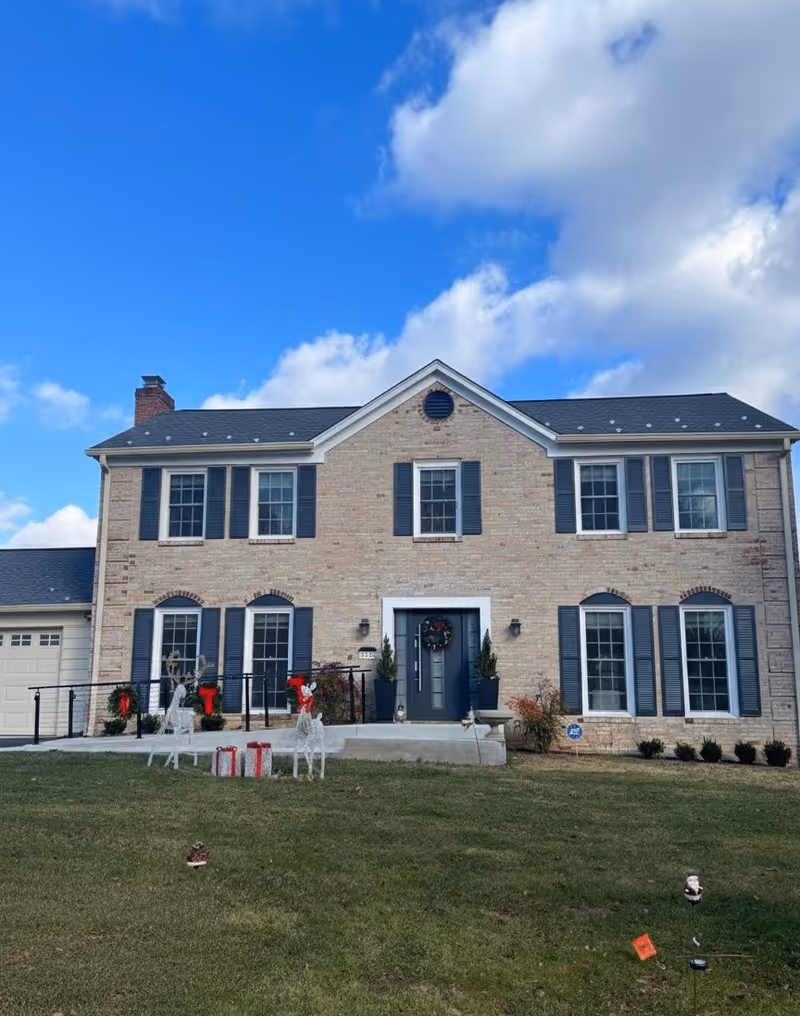 Aster Group Home exterior: two-story brick building with blue shutters, wreath, and decorations in the yard.