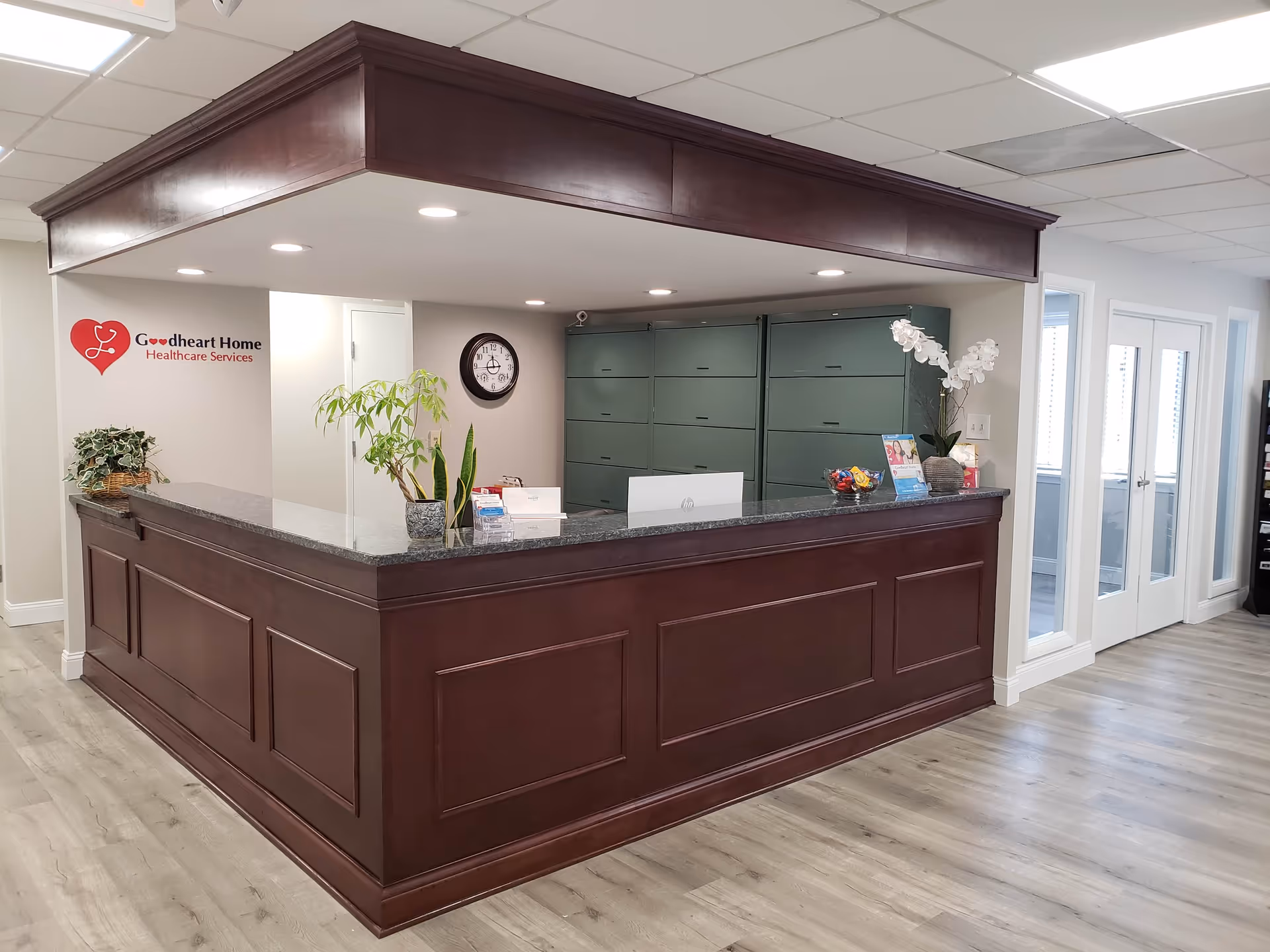 Dark wooden reception desk in a bright lobby with Goodheart signage and green mail lockers.